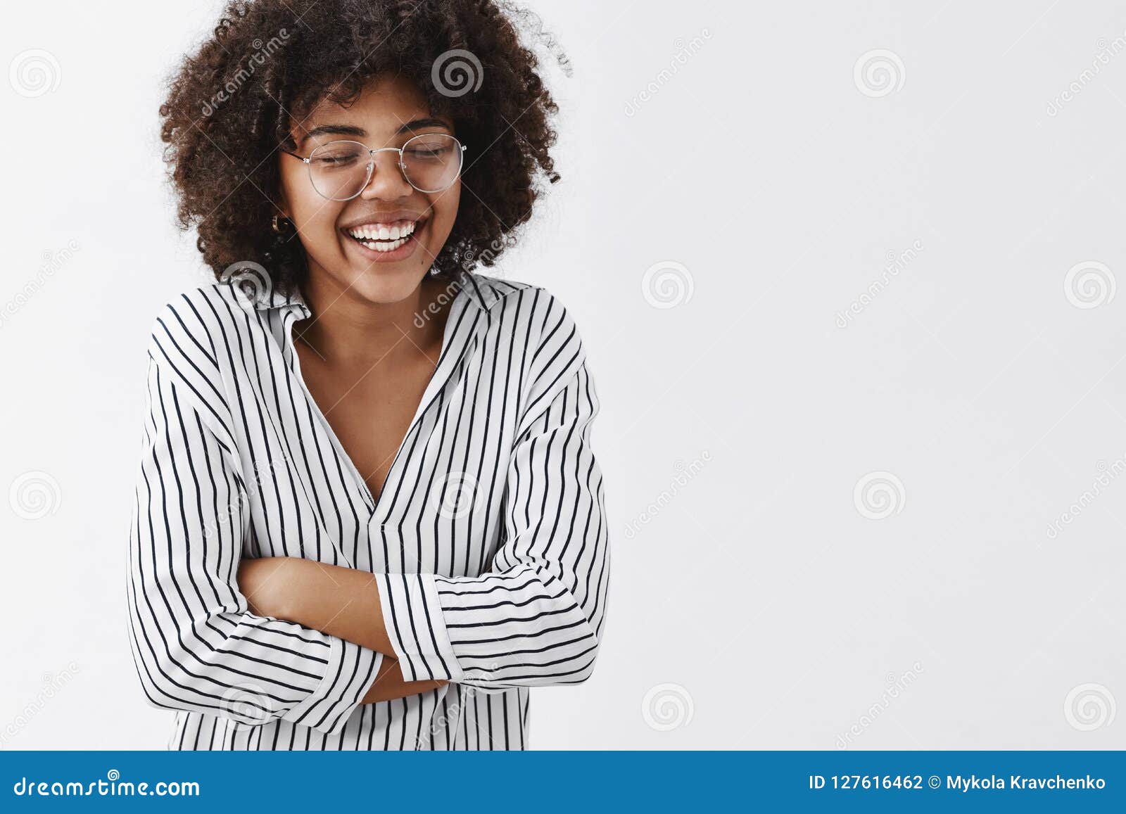 belly aching from laughter. amused and carefree attractive african american woman in striped blouse and glasses closing