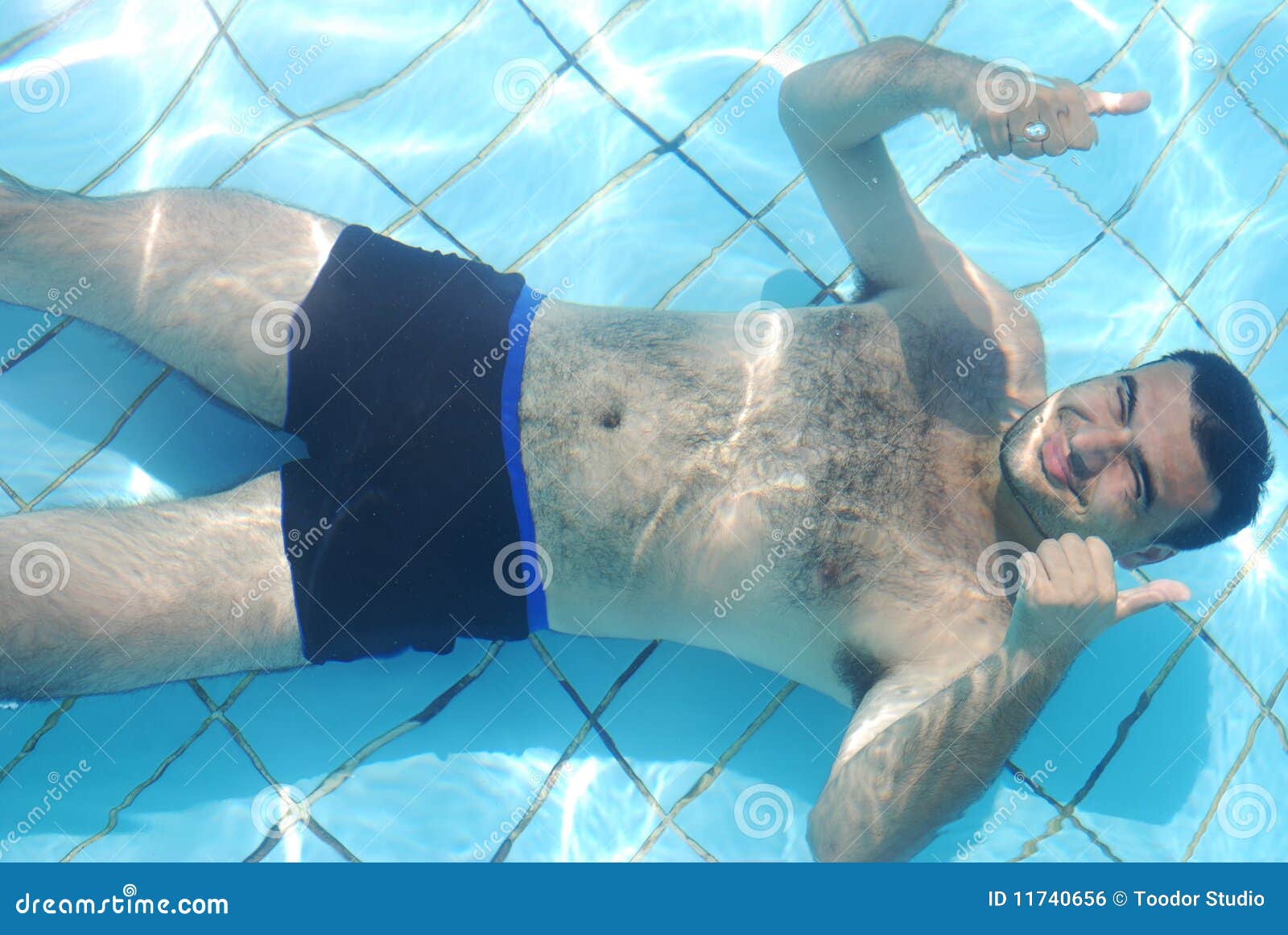 Bemannen Sie die Entspannung an der Unterseite des Swimmingpools. Junger Mann, der an der Unterseite des Swimmingpools stillsteht