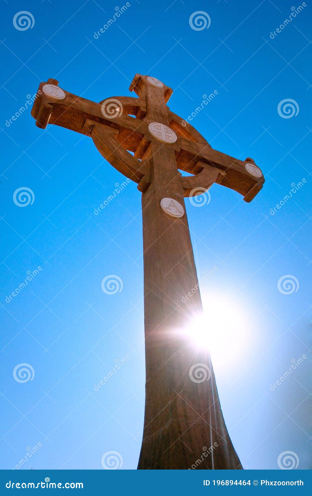 benedictine wooden cross with sunflare against deep blue sky