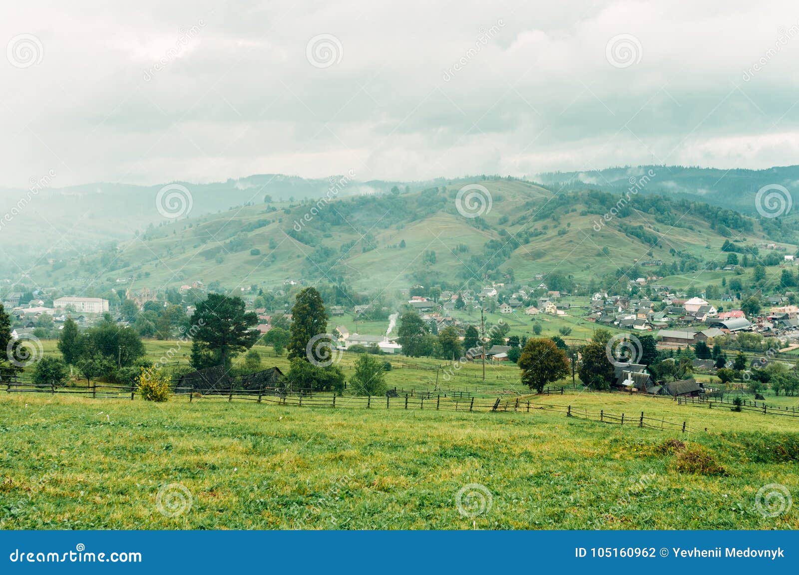 Berglandschaft mit einem kleinen gemütlichen Dorf auf dem flachen Land, ein Platz im Herbstnebel