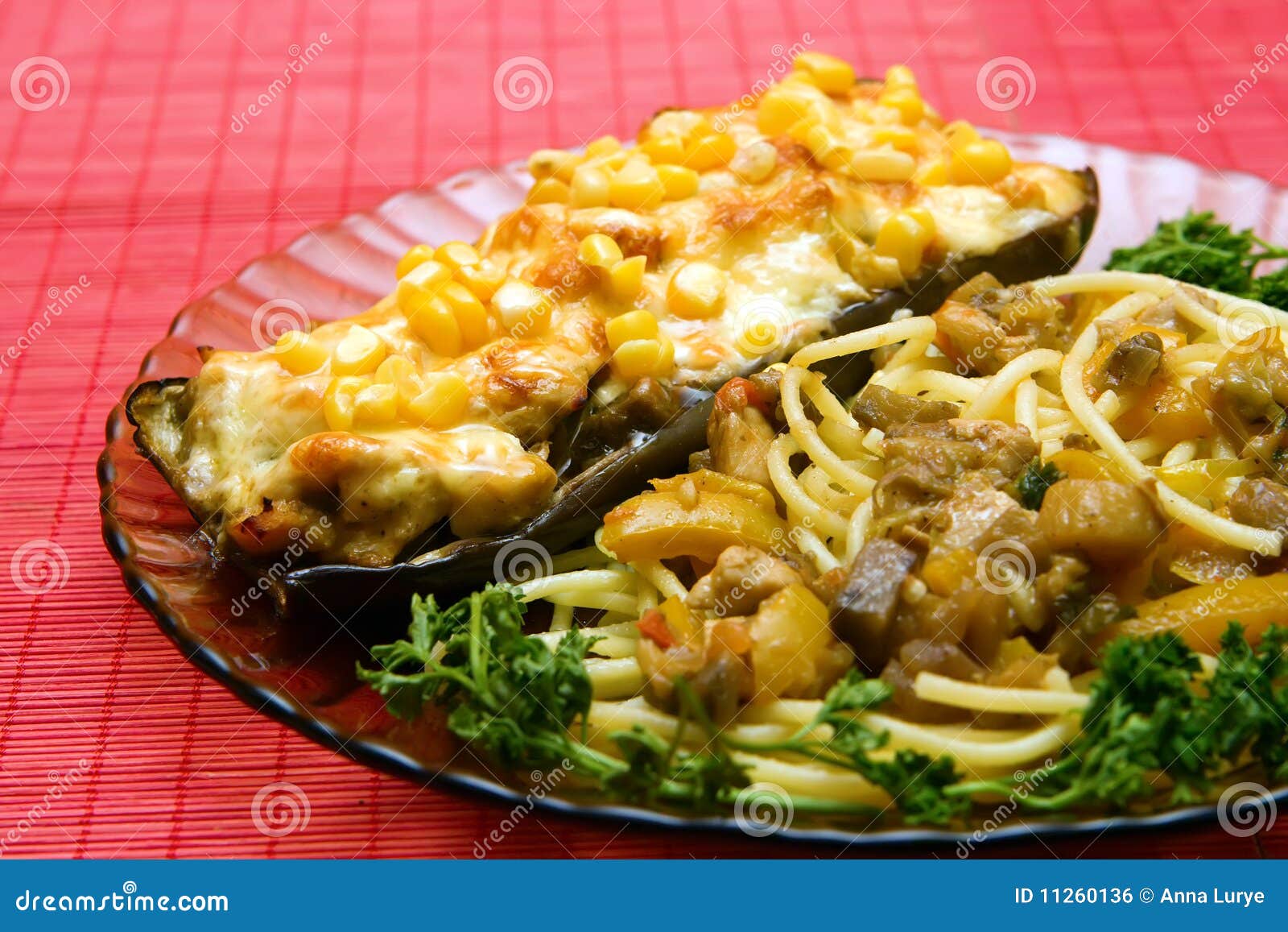 Placa do close up com o barco feito da beringela sob o queijo e o milho com macarrão e vegetais