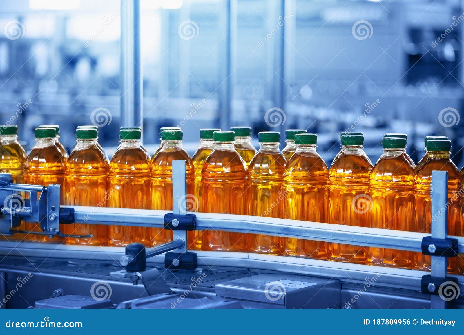 beverage factory, conveyor belt with juice in bottles, industrial interior in blue color, food and drink production line