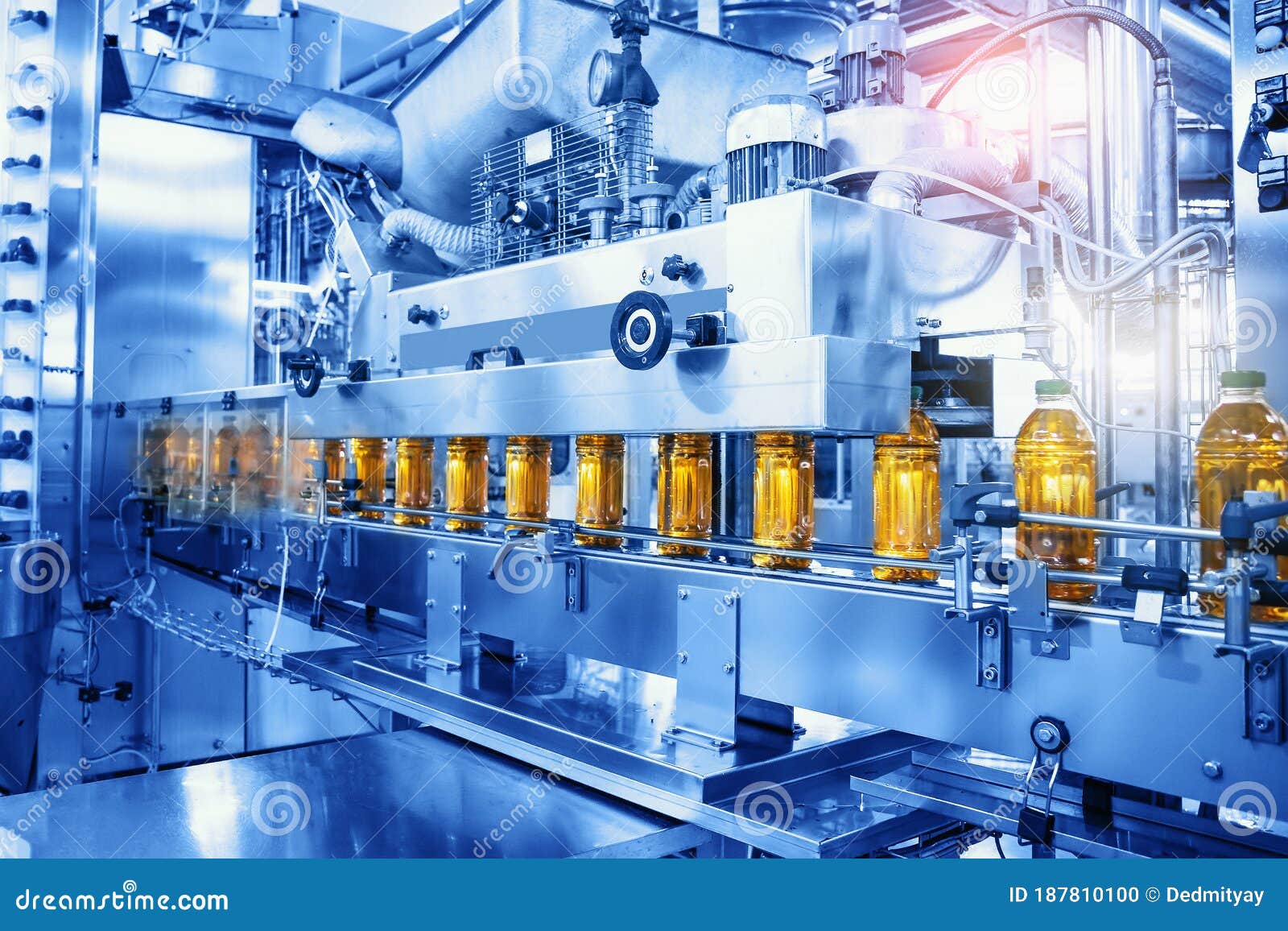 beverage factory, conveyor belt with juice in bottles, industrial interior in blue color, food and drink production line