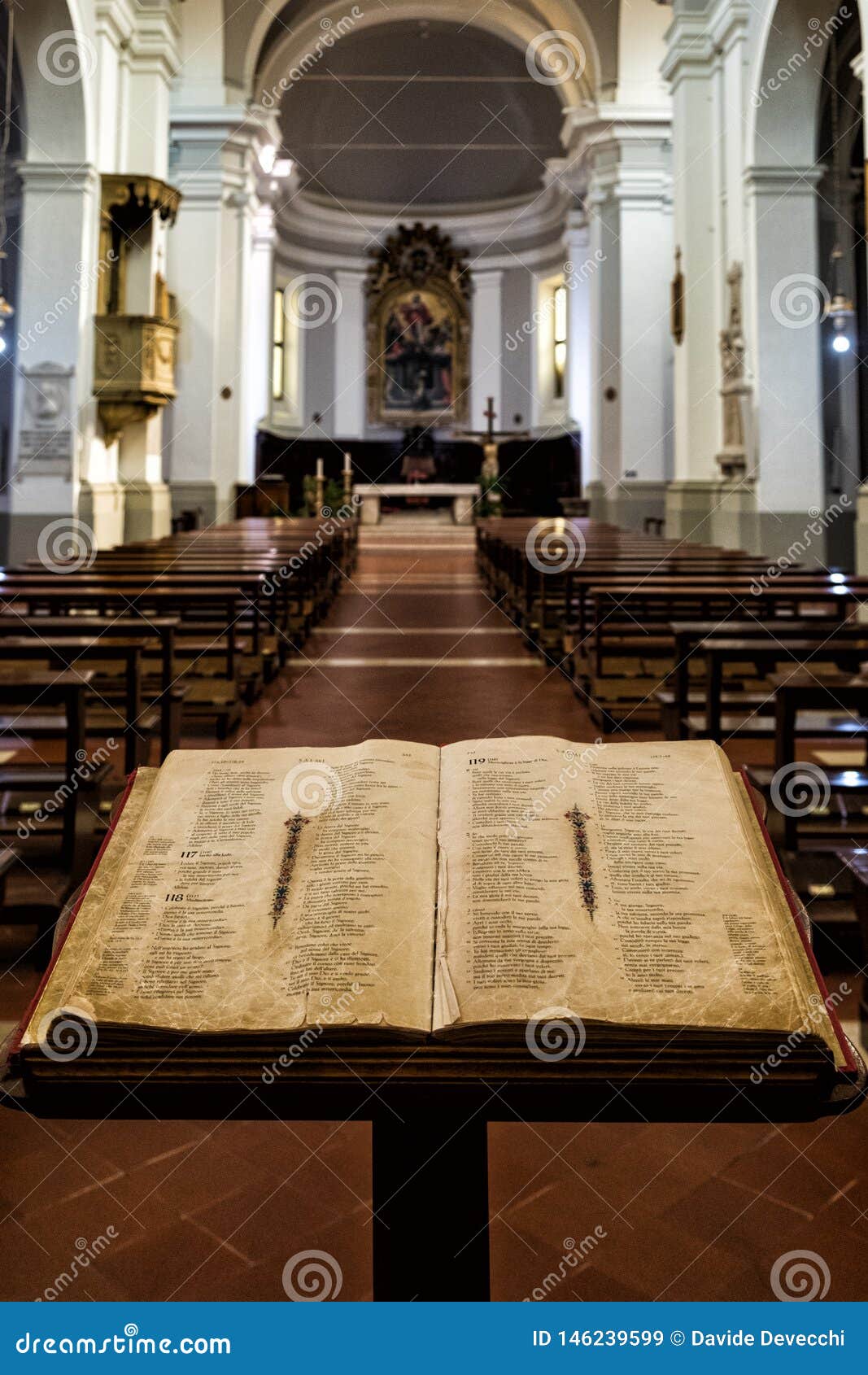 a bible open on a lectern at the entrance of a catholic church in urbino, central italy