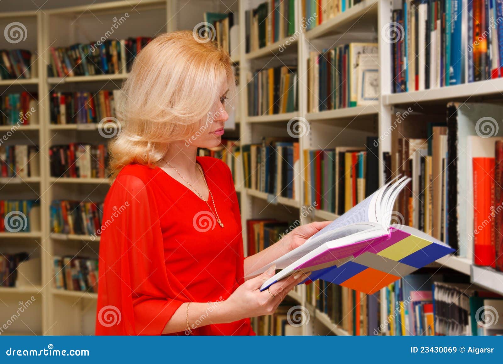 Biblioteczna kobieta. Dorosły książka cieszy się kobiet jej bibliotecznych ładnych target2323_0_ potomstwa