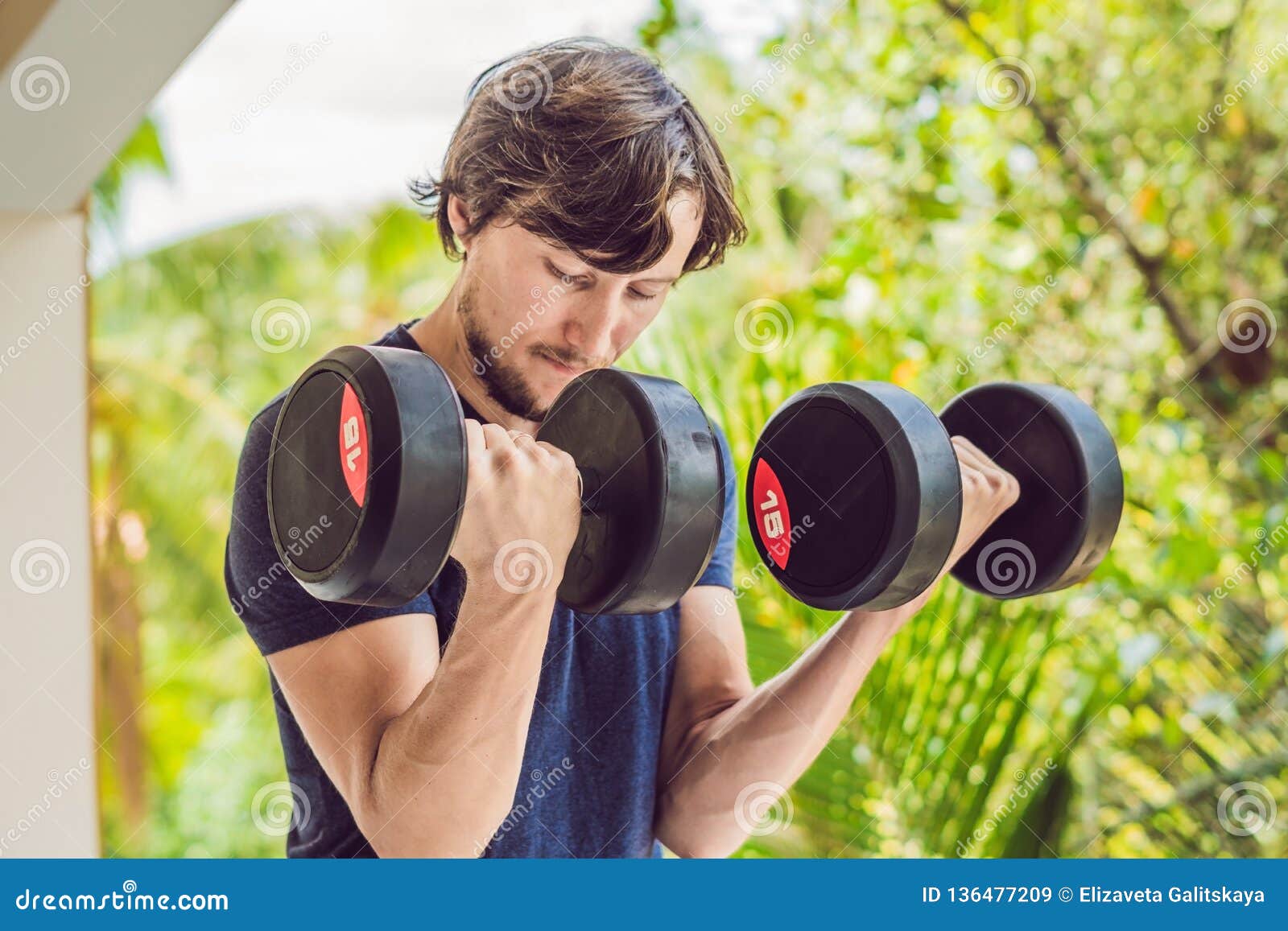 bicep curl - weight training fitness man outside working out arms lifting dumbbells doing biceps curls. male sports