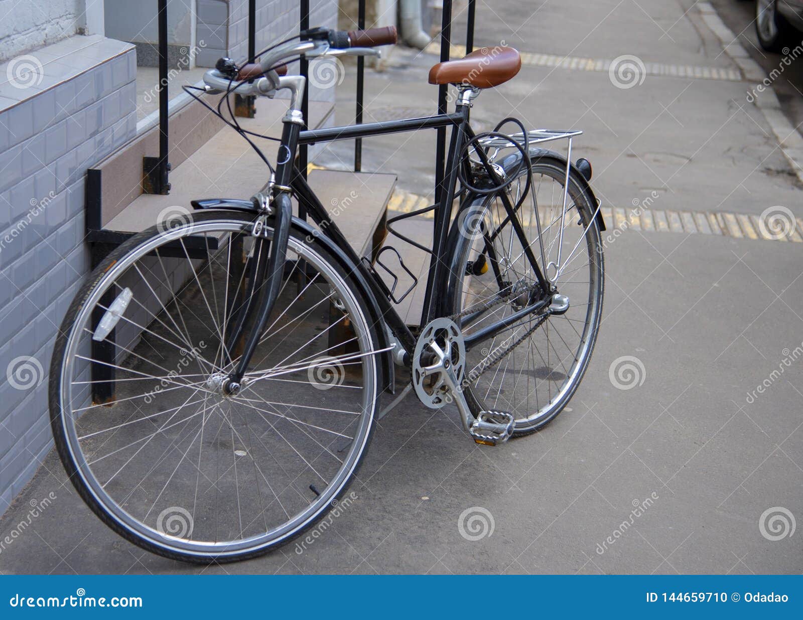 A Bicycle with Big Thin Wheels is Leaning Against the Porch. Stock
