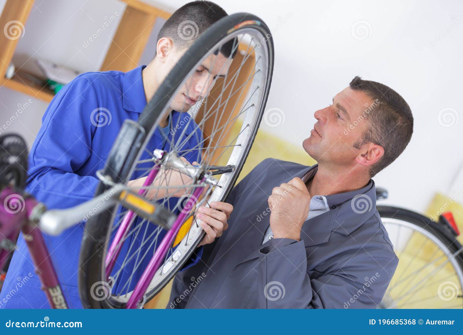 Bicycle Mechanic with Wrench Changing Wheel on Bike in Stock