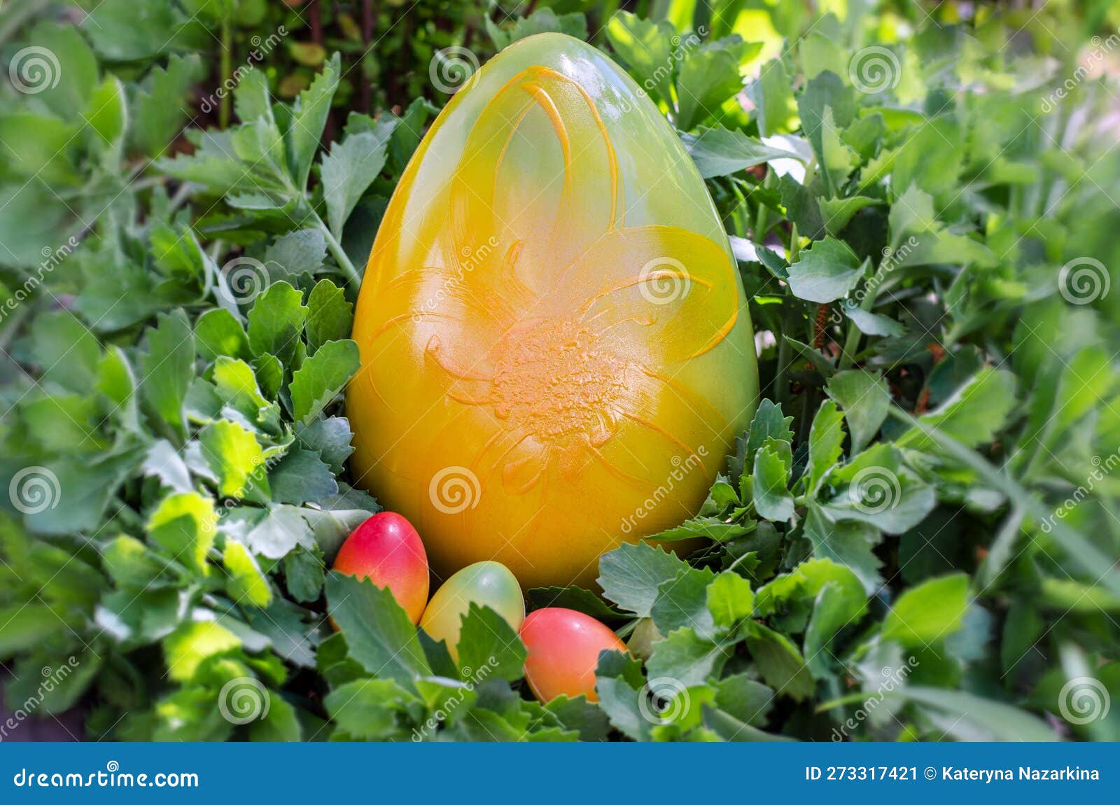Big Chocolate Easter Egg in Green Grass with Small Chocolate Eggs