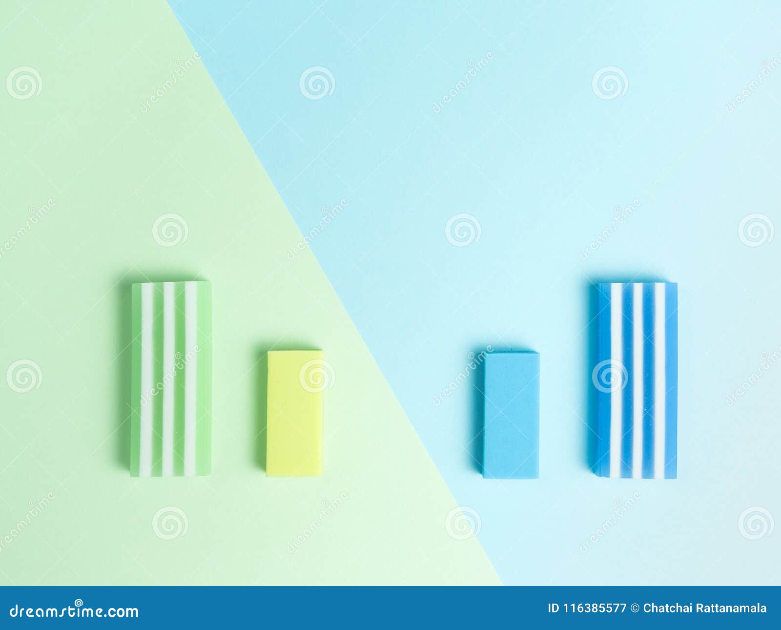 big and little green eraser and blue eraser on green and light blue background