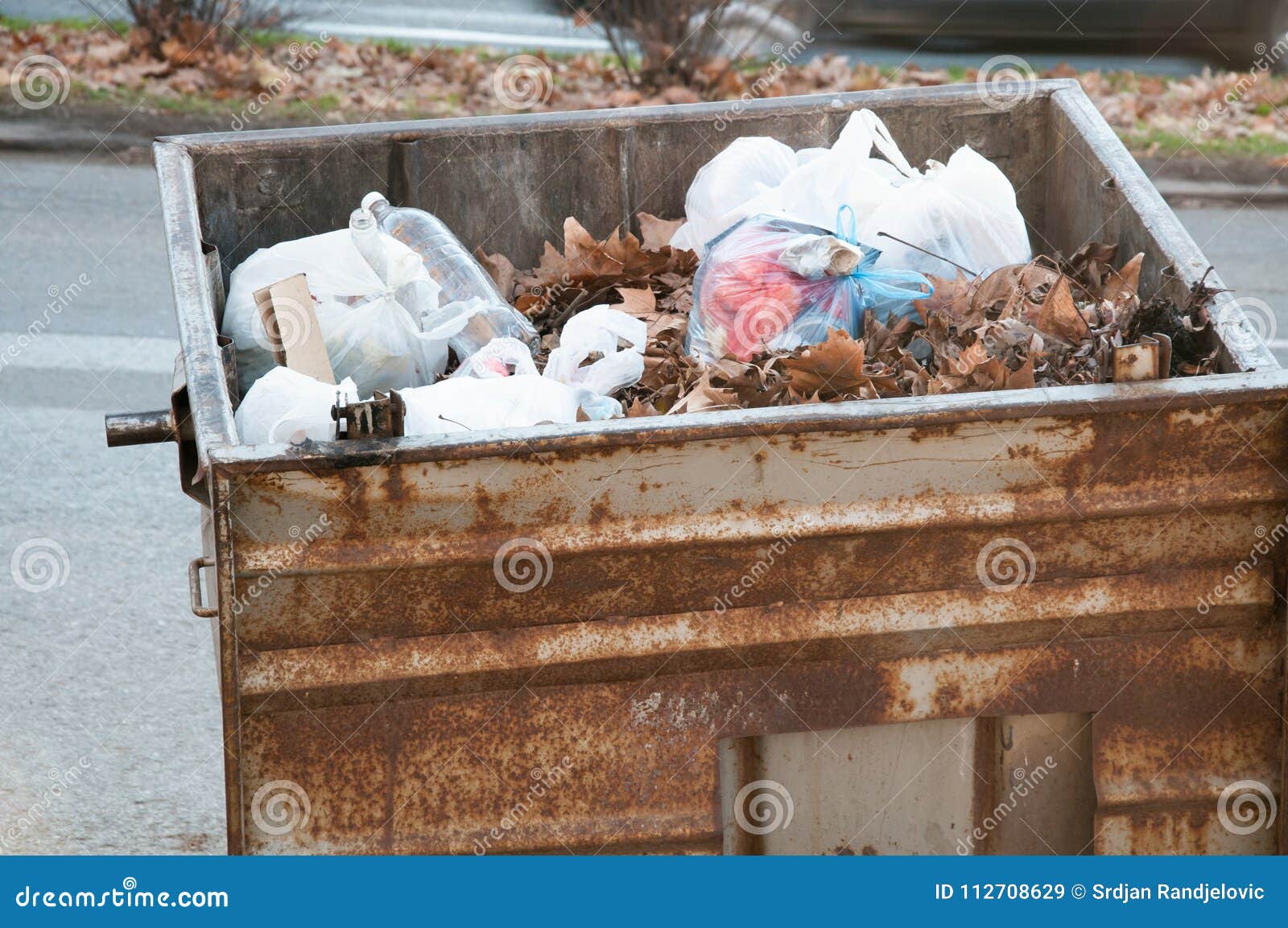 Big two metal dumpster garbage cans full of overflow litter and junk  polluting the street in the city Stock Photo