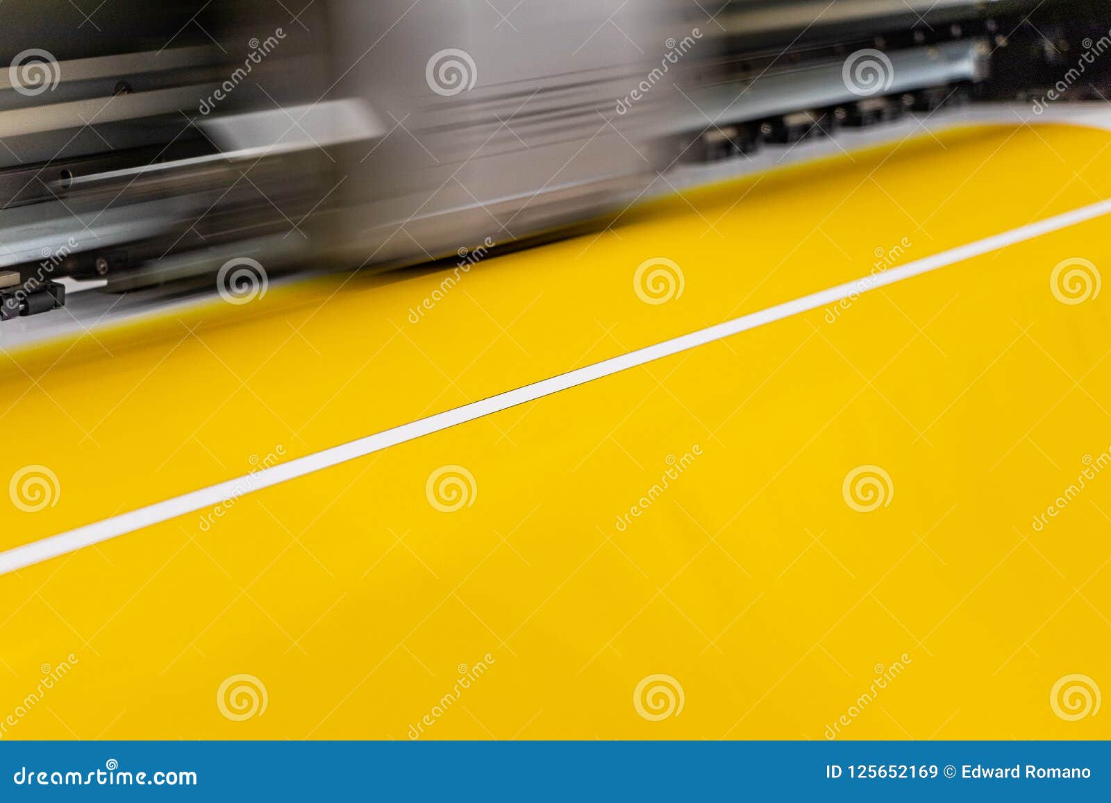 big professional printer, processing a large scale glossy sheet of yellow paper rolls for color sampling.