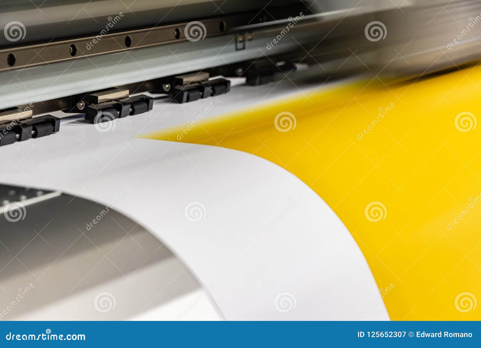 big professional printer, processing a large scale glossy sheet of yellow paper rolls for color sampling.