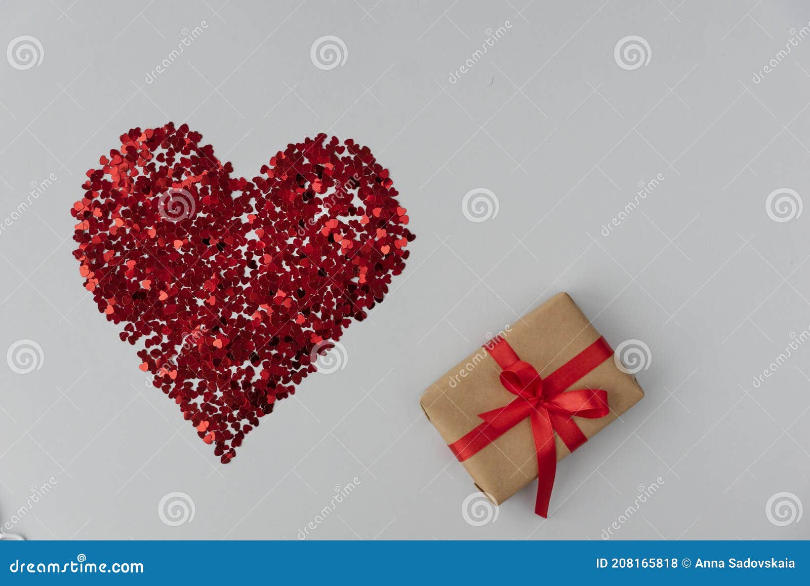 big red heart made from little glittering confeti of heart s, gift box with red ribbon is near,