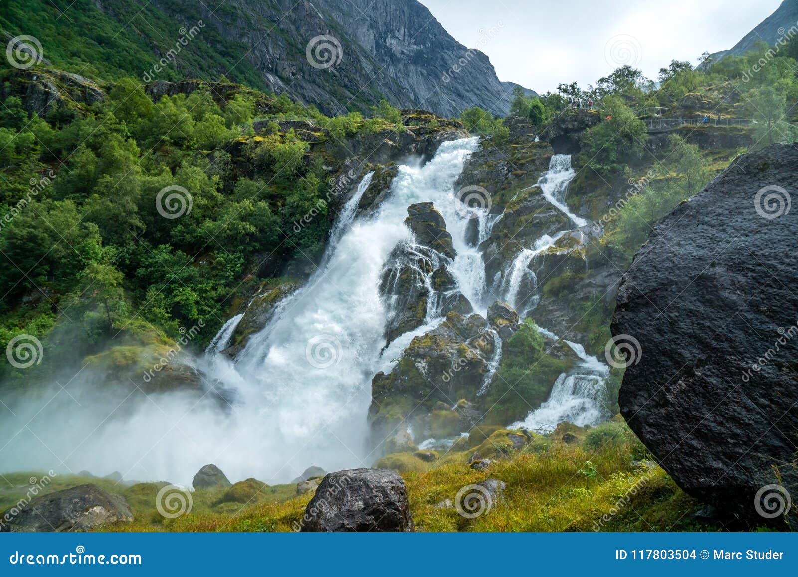 big waterfall with stones and green land