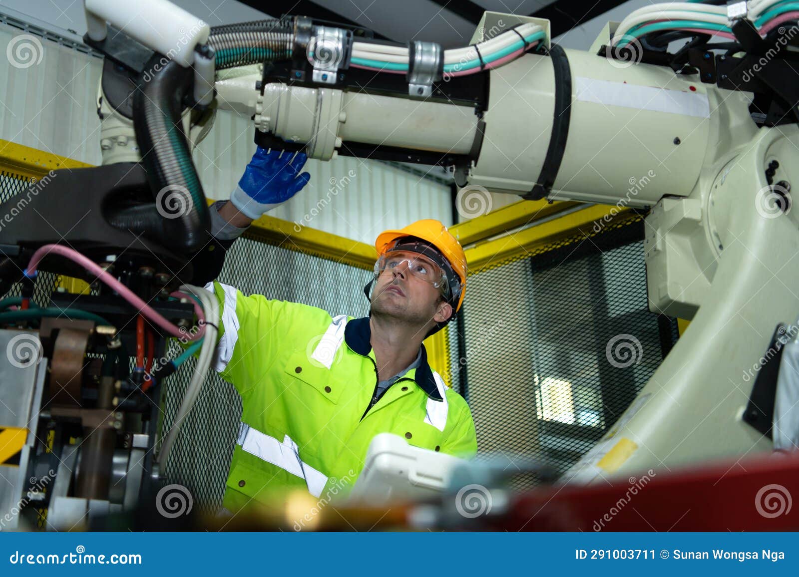 a big welding robot is being inspected and controlled by a robotics engineer.