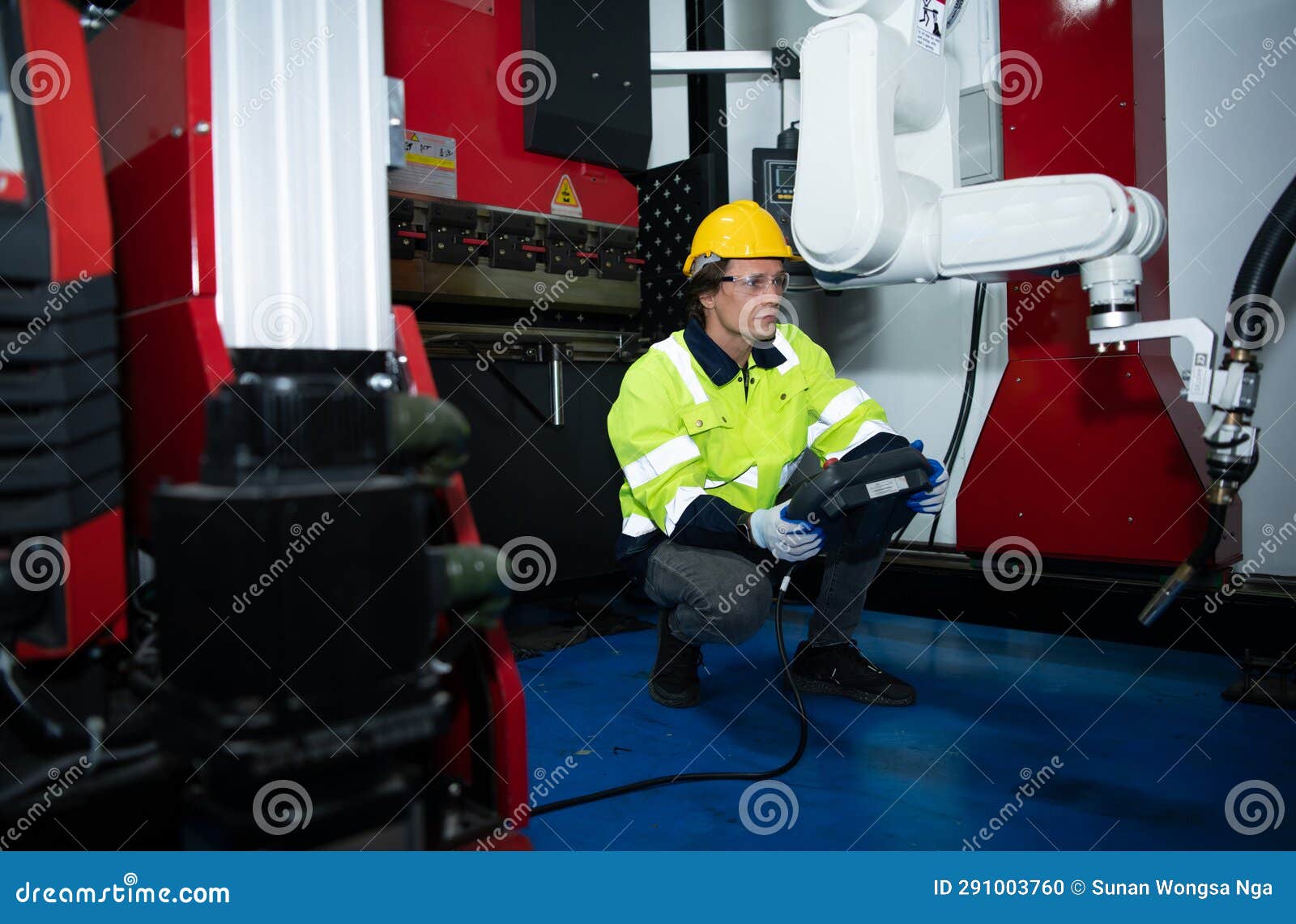 a big welding robot is being inspected and controlled by a robotics engineer.
