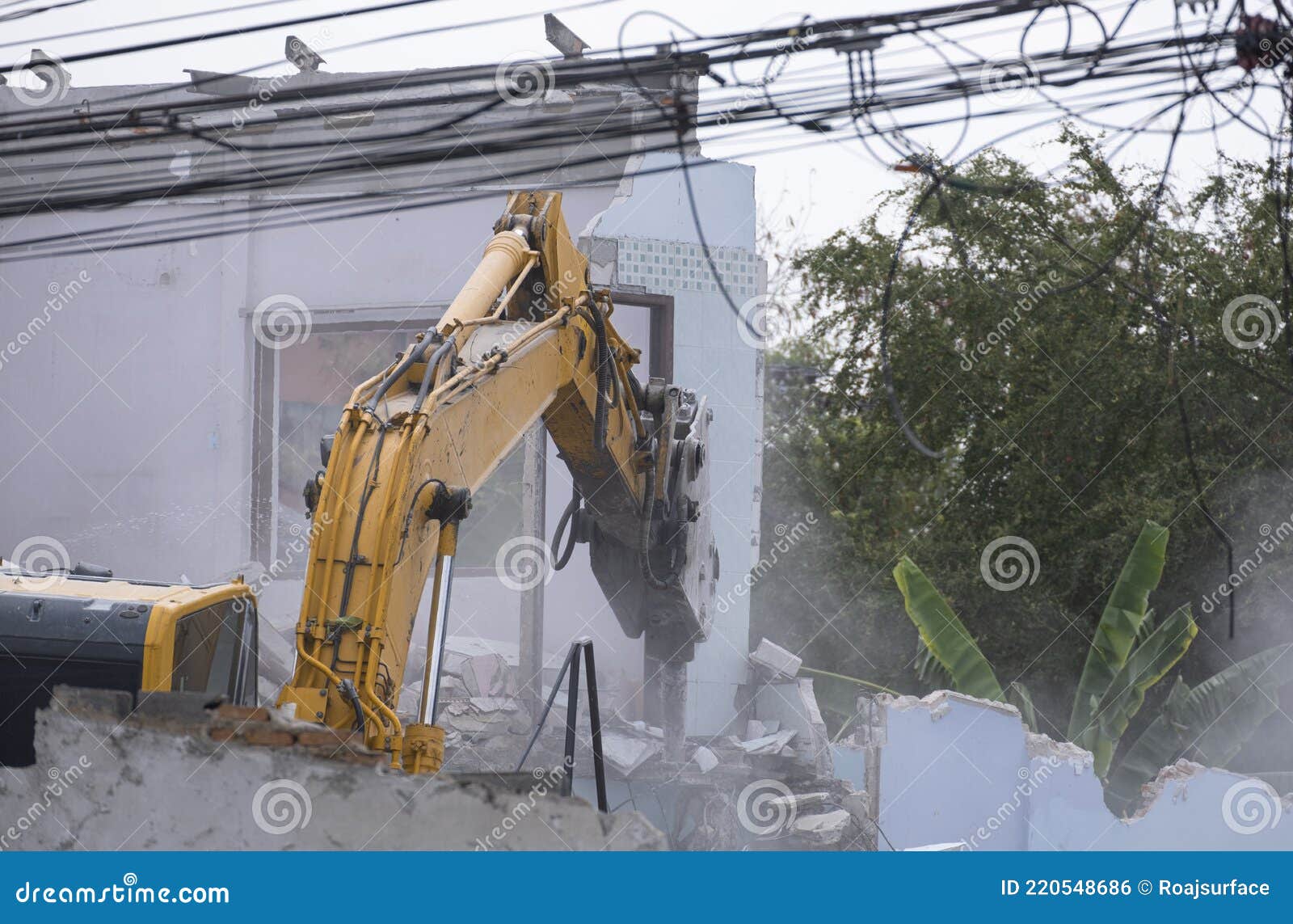 big yellow excavator removal home building by destroy concrete wall. uproot old construction house for development new project