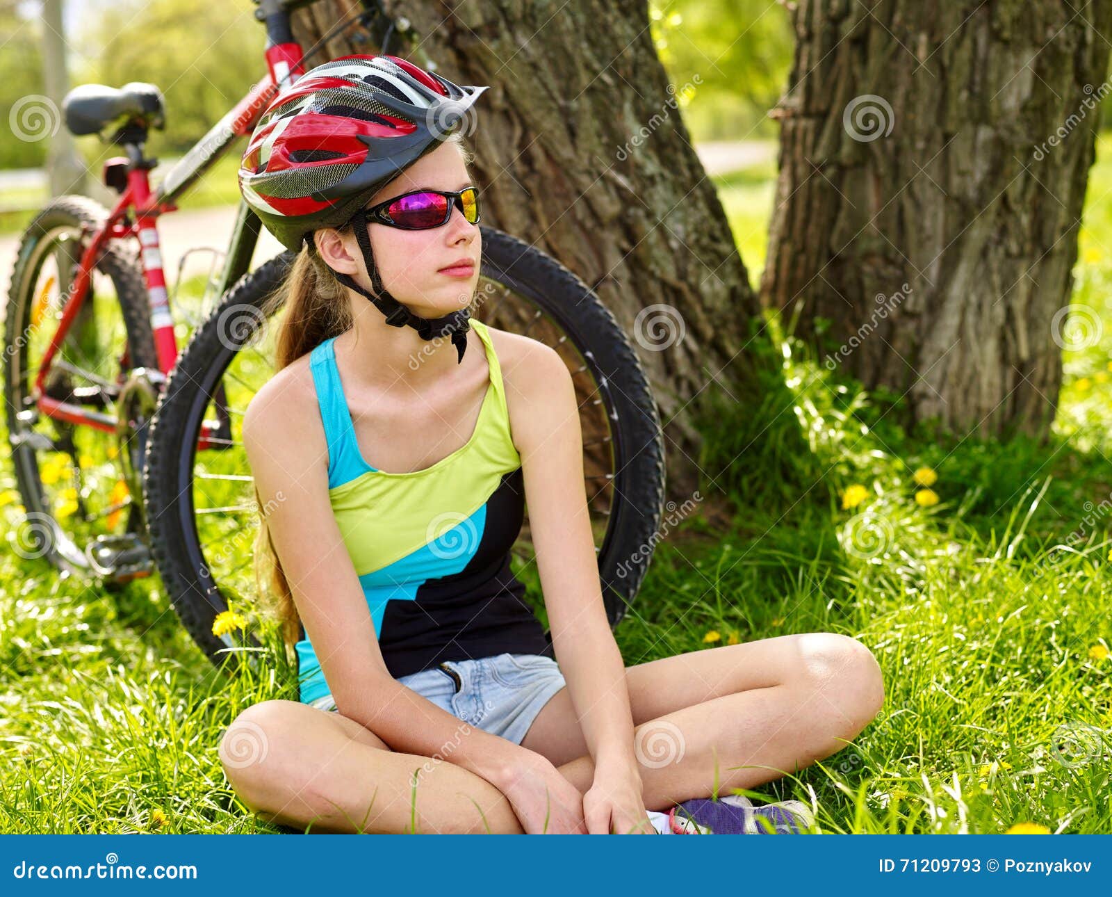 bikes cycling girl wearing helmet have a rest sitting under tree.