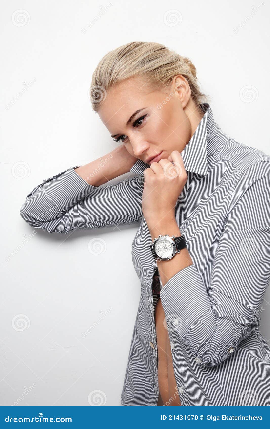 Young beautiful blond slim thoughtful woman listening her biological clock ticking, over white wall