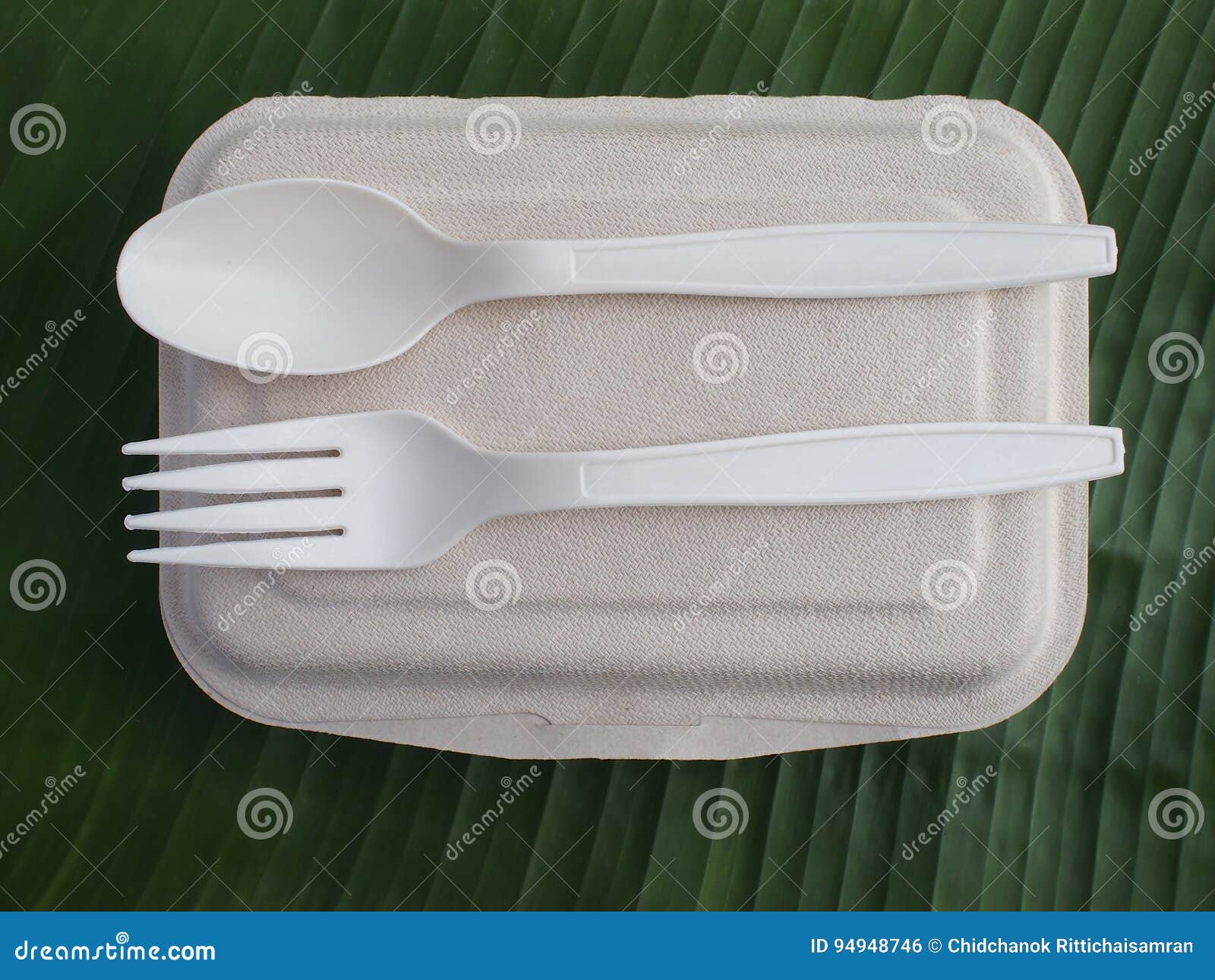 bioplastic spoon fork and disposable lunch box on banana leaf