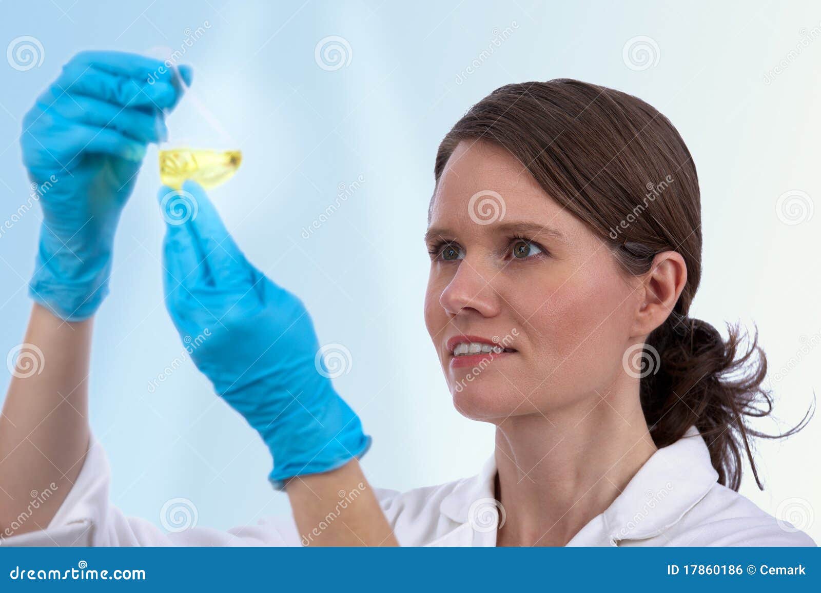 Biotechnician caucasien femelle dans le laboratoire examinant le liquide jaune dans une fiole conique. Orientation sélectrice sur le scientifique