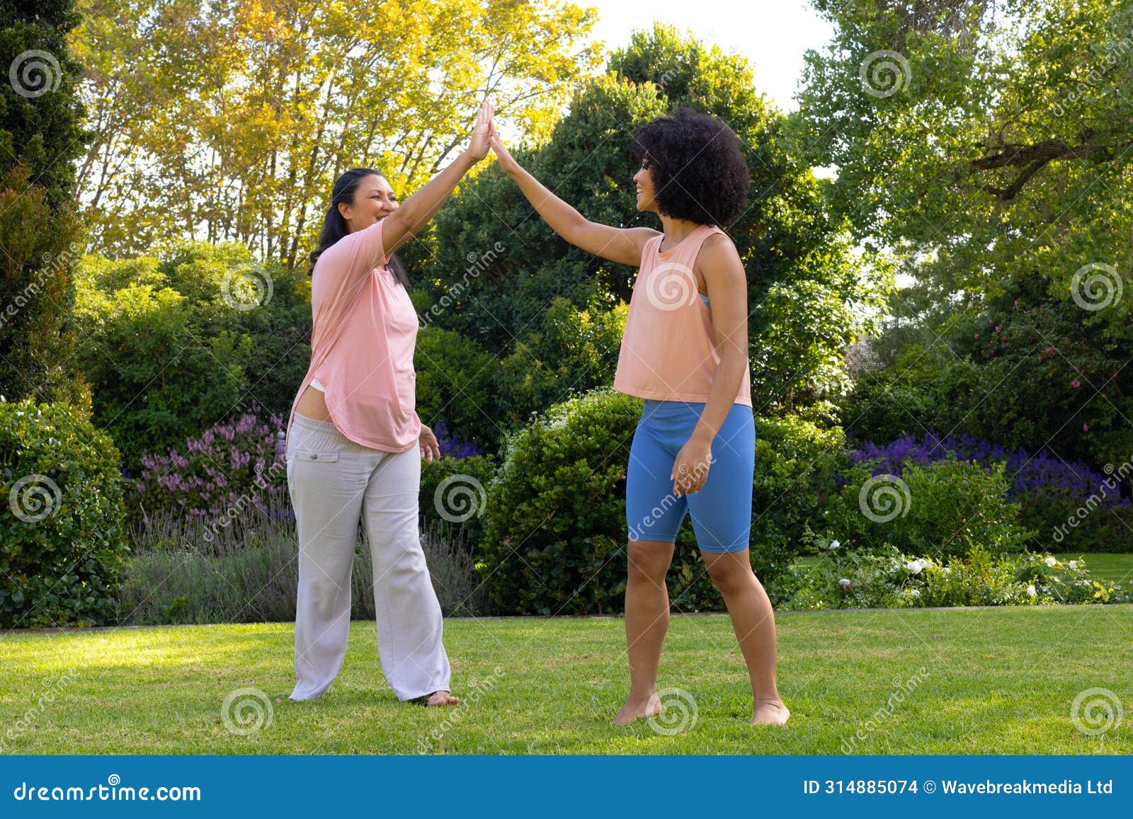 biracial mother and daughter are high-fiving in garden at home