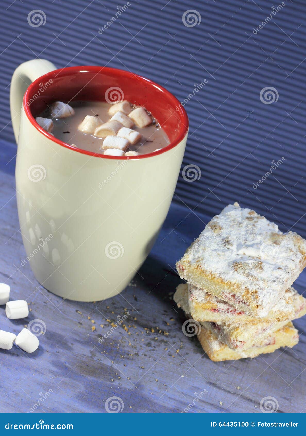 Biscotti e cacao. Tazza di cacao caldo con le caramelle gommosa e molle ed i biscotti su un fondo blu Fuoco molle