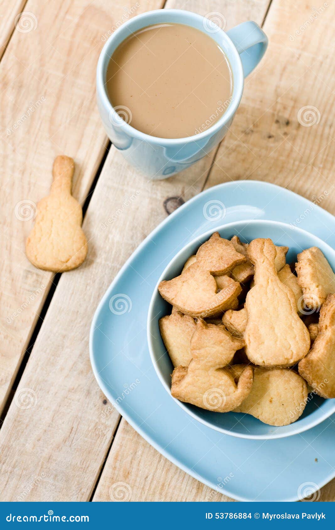 Biscotti saporiti dolci nel piatto blu, una tazza di caffè con latte. Biscotti saporiti dolci in piatto blu, tazza di caffè con latte e taccuino su fondo non dipinto di legno