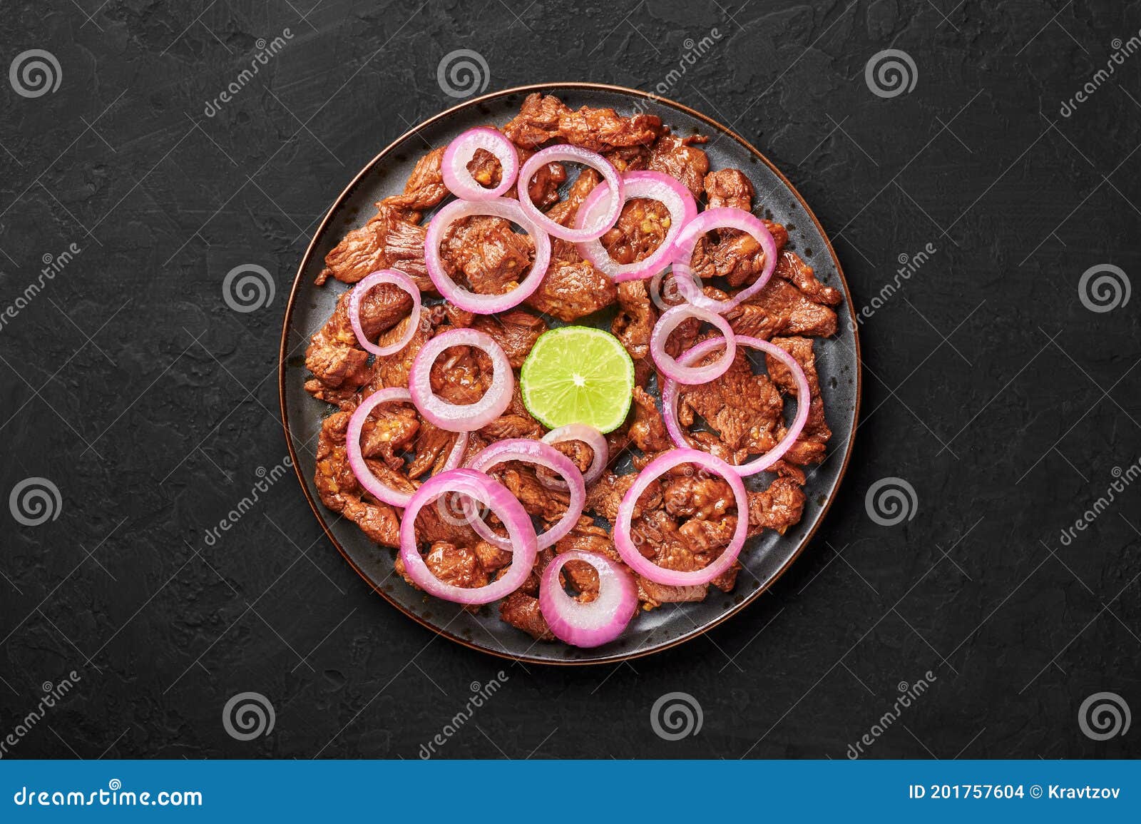 bistek tagalog or bistec encebollado on black plate on slate table top. filipino spanish cuisine beef steak with onion
