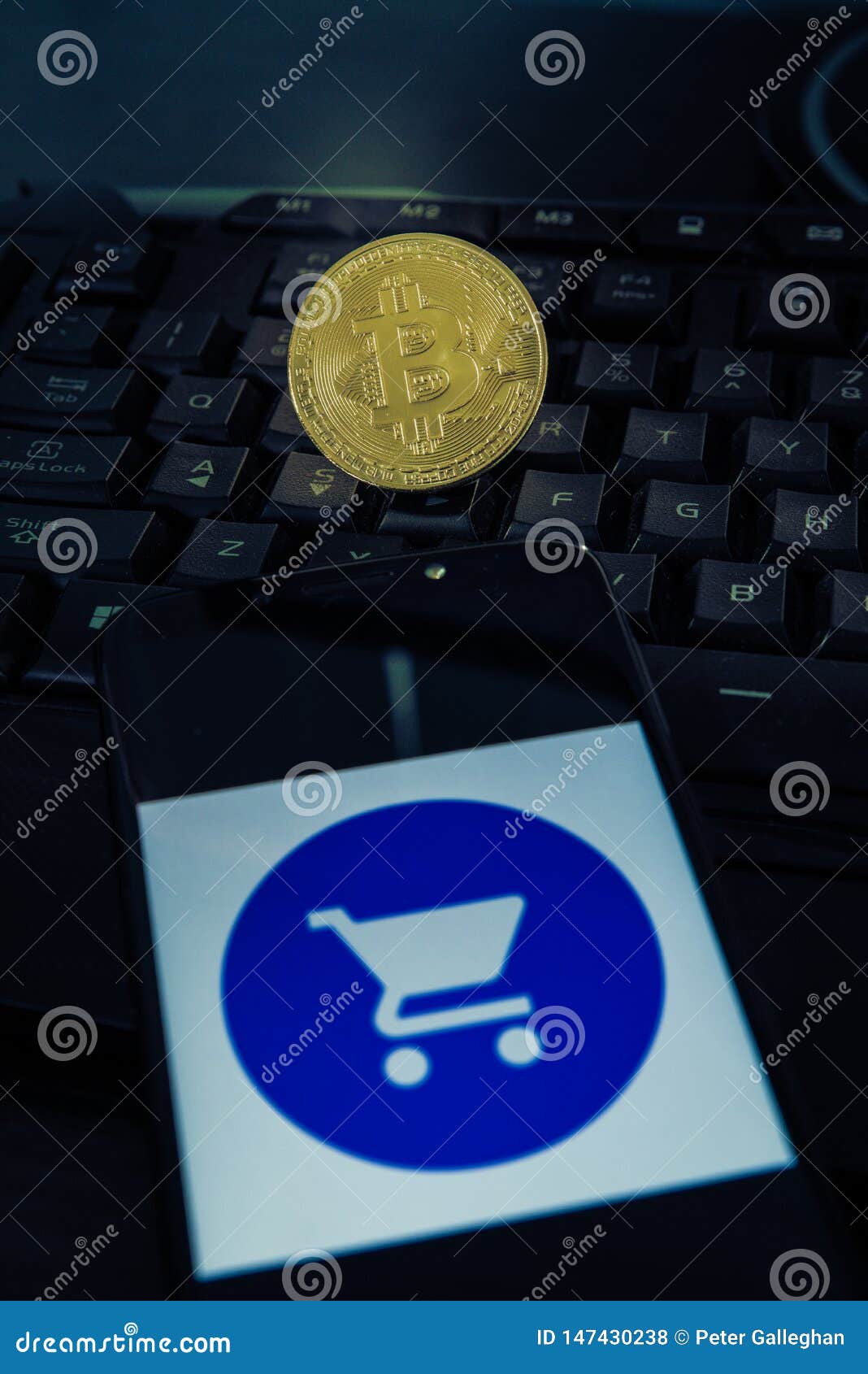 Bitcoin on a Keyboard and a Shopping Cart Symbol on a Smartphone Stock