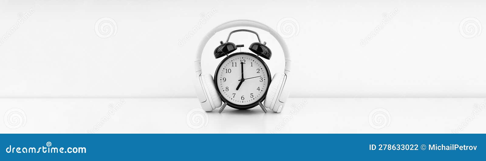 Black Alarm Clock with Headphones on White Wall Background Stock Photo