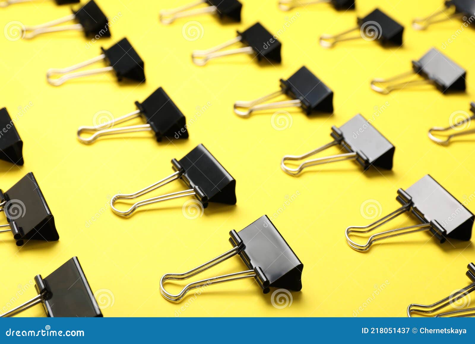 Black Binder Clips on Yellow Background. Stationery Items Stock Image