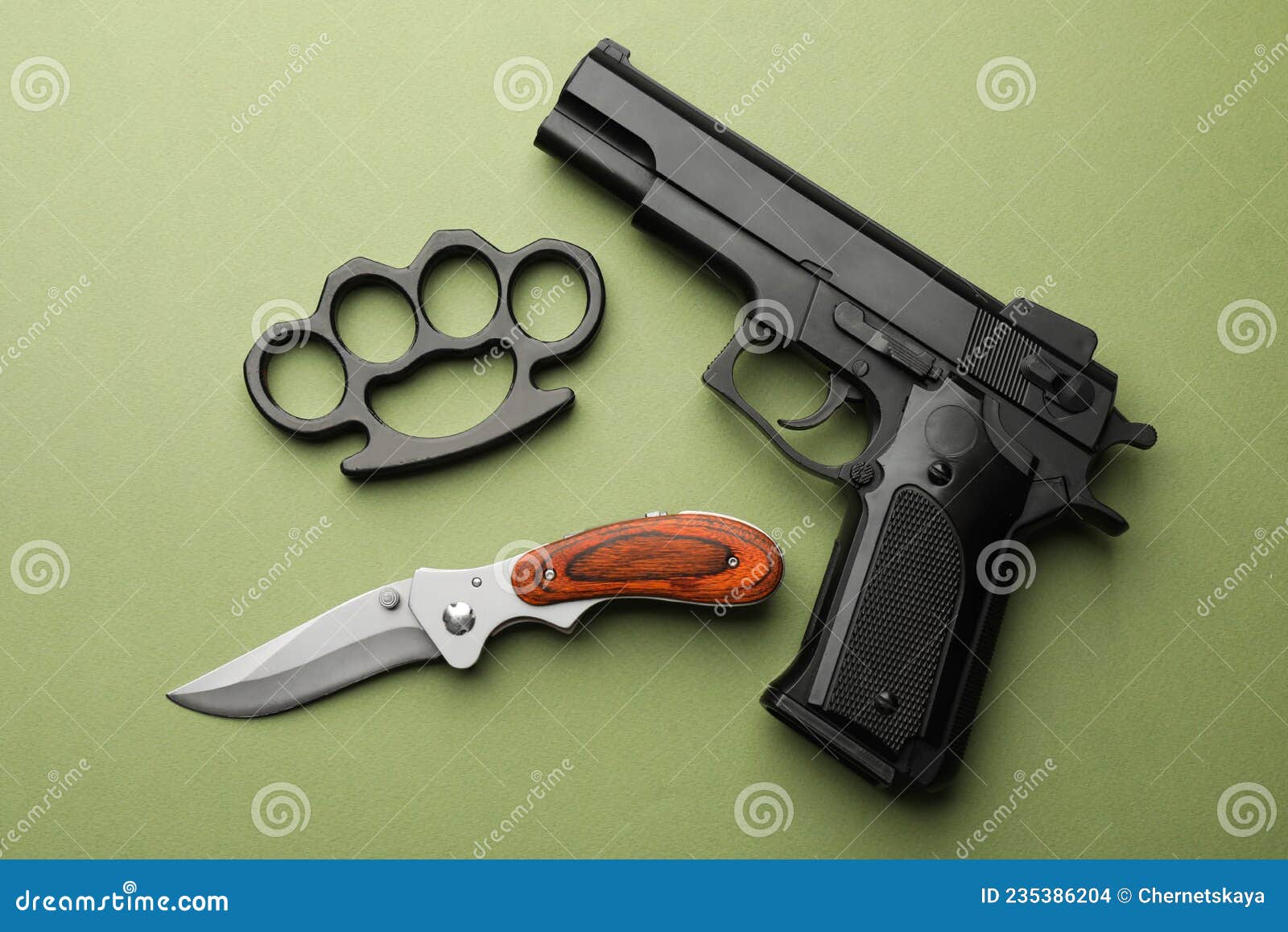 Black Brass Knuckles, Gun and Knife on Green Background, Flat Lay