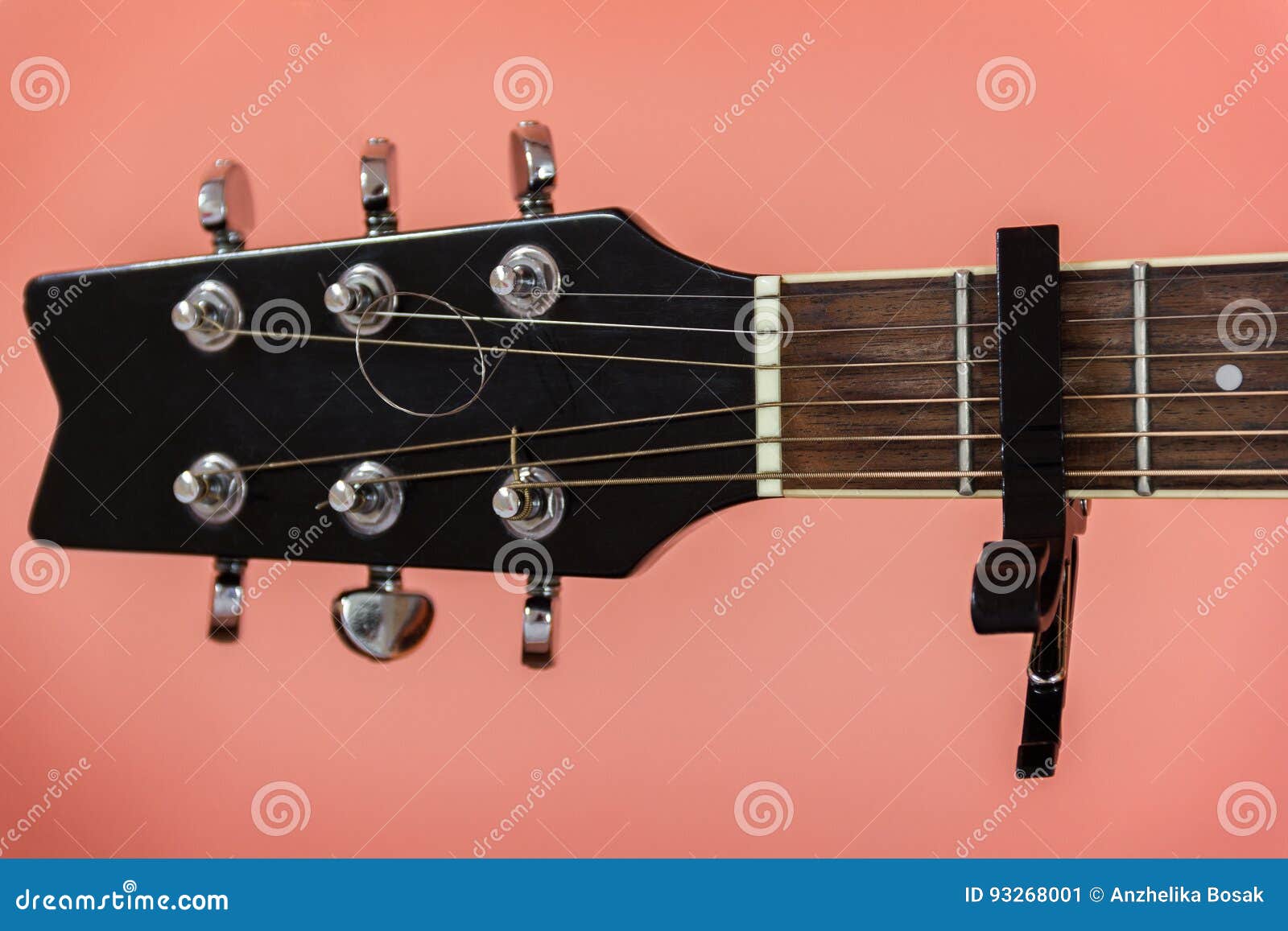 Black capo on a guitar on a peach Colour background