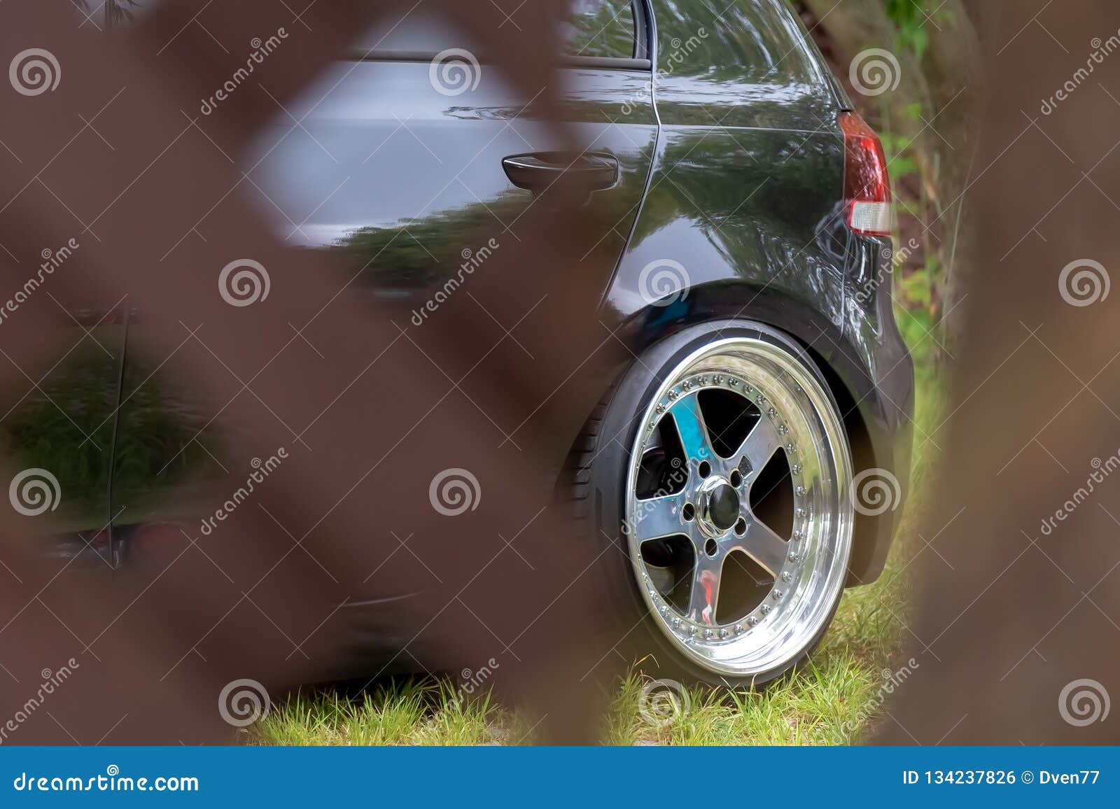Black Car with Tuned Wide Chrome Wheels Behind the Barrier Stock Photo