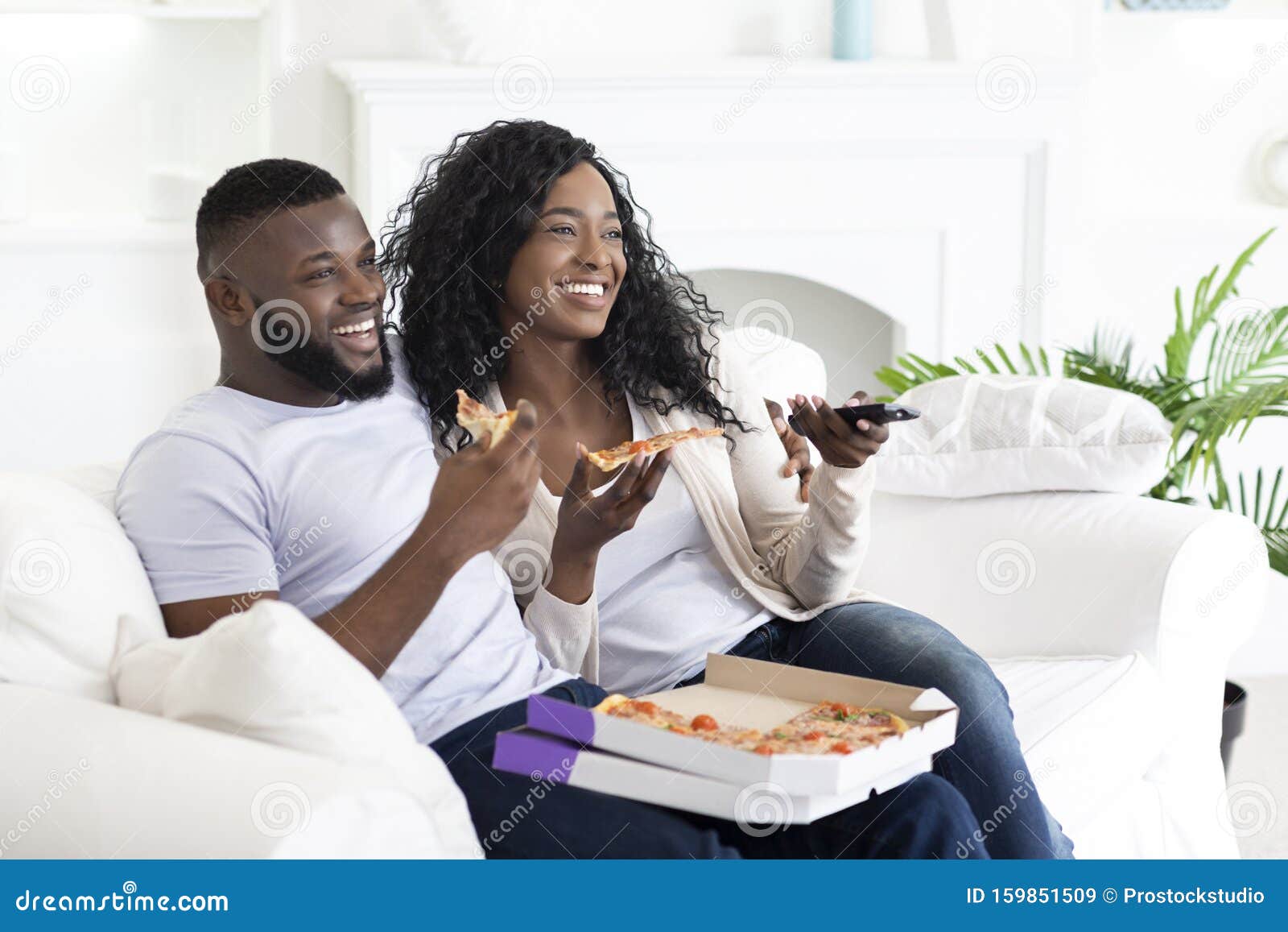 Happy african american friends eating pizza at home Stock Photo by  Prostock-studio