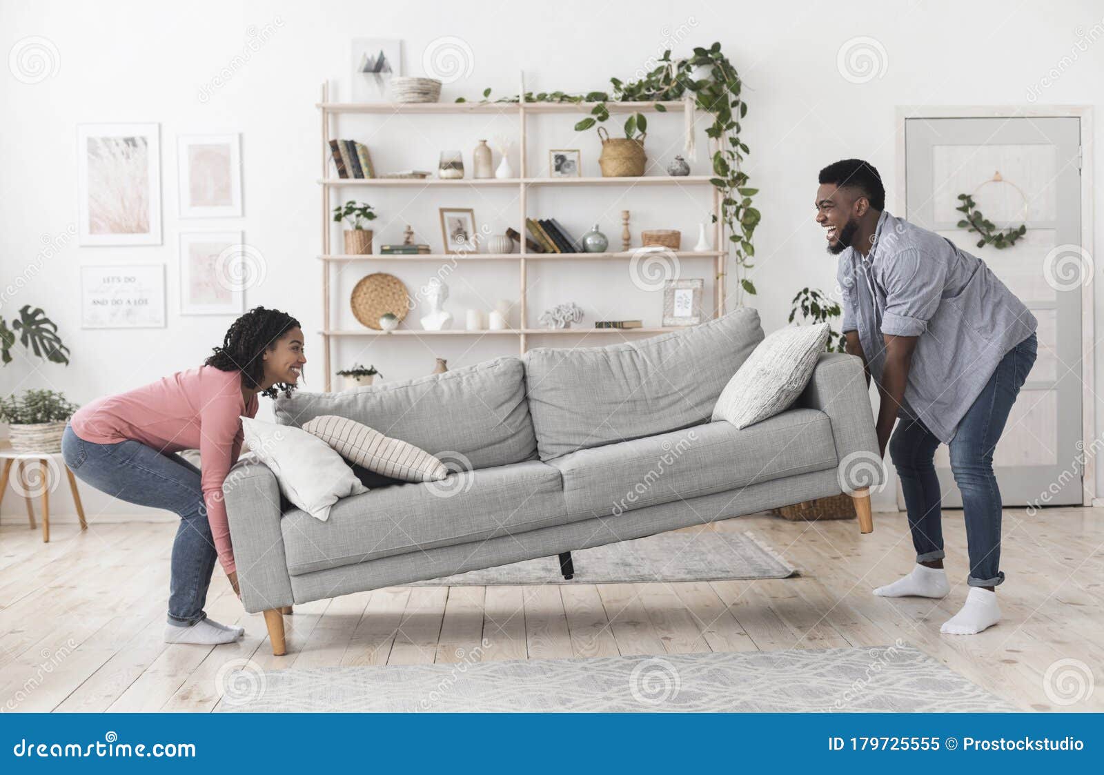 Black Couple Moving Sofa In Living Room