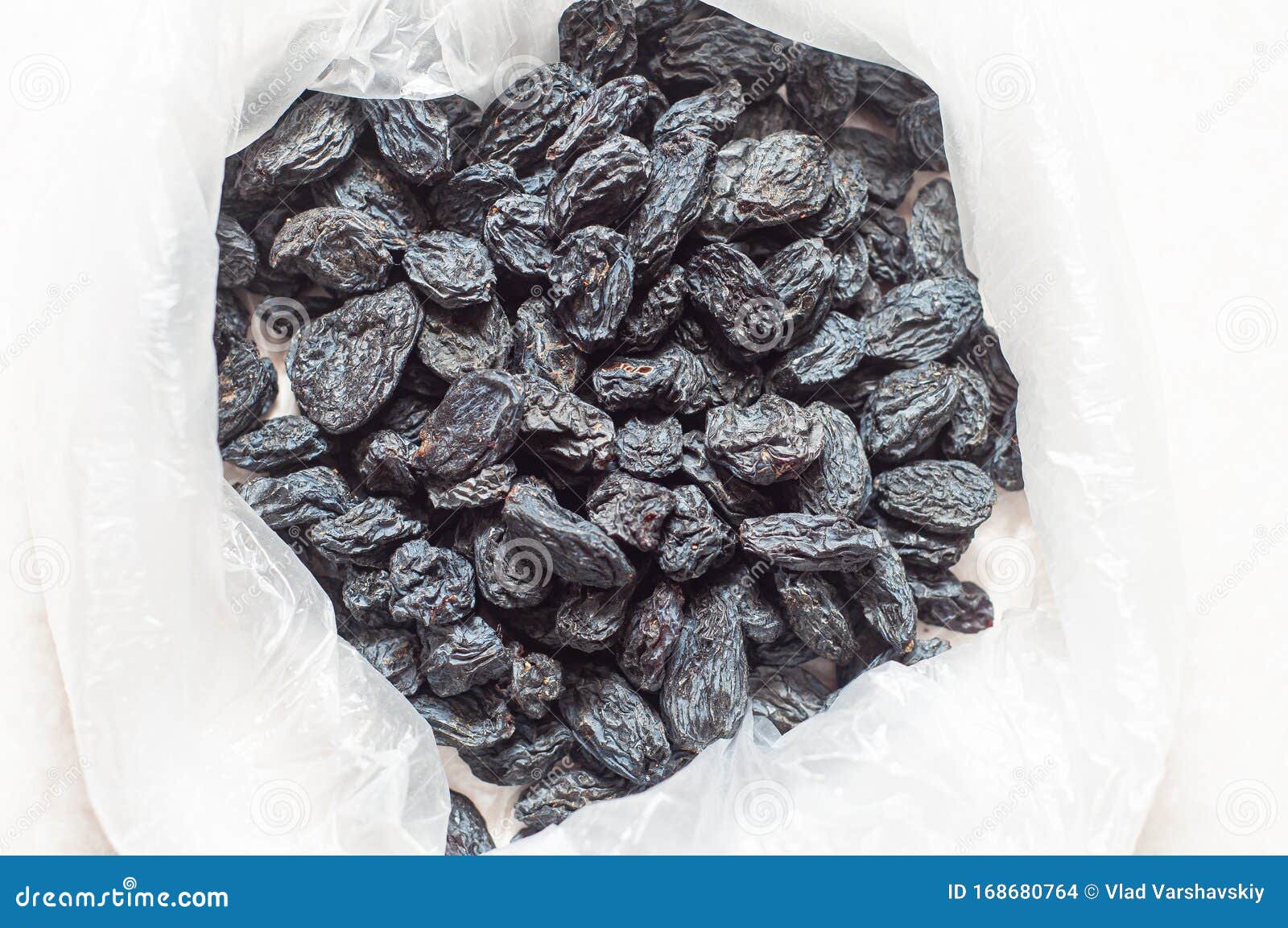 Black Dried Raisins in a Plastic Bag on a White Table. the Rate of ...