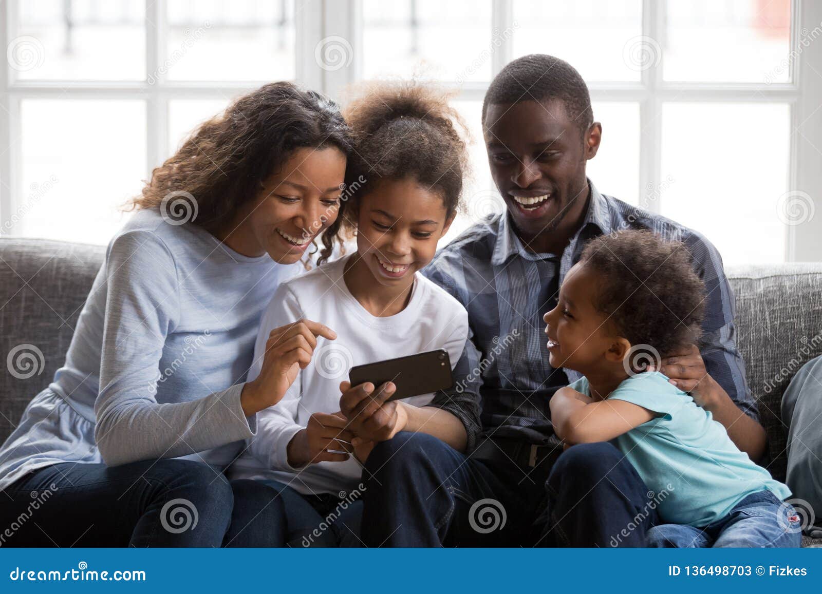 black family and kids laughing watching funny video on phone