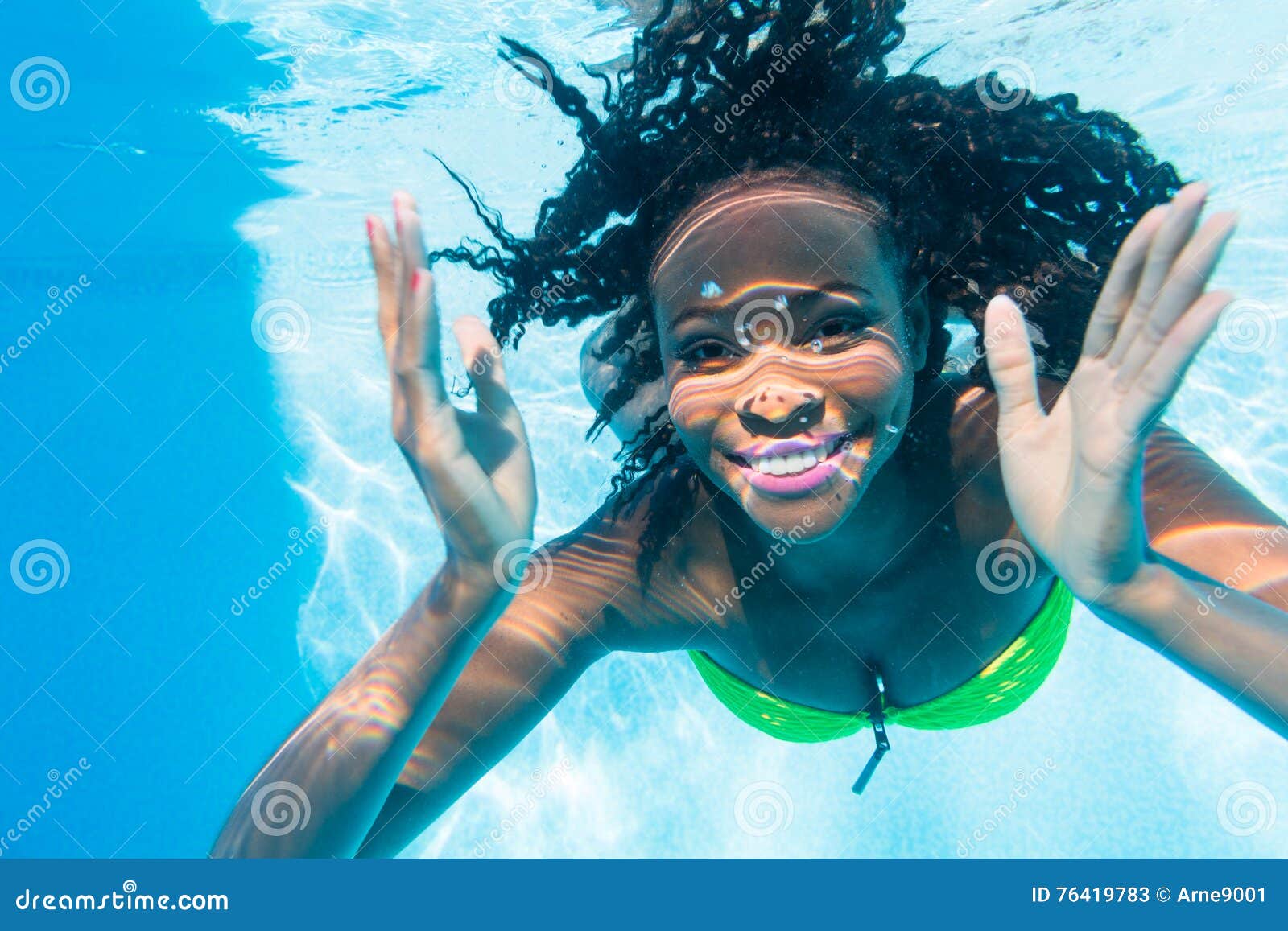 black girl diving in swimming pool at vacation