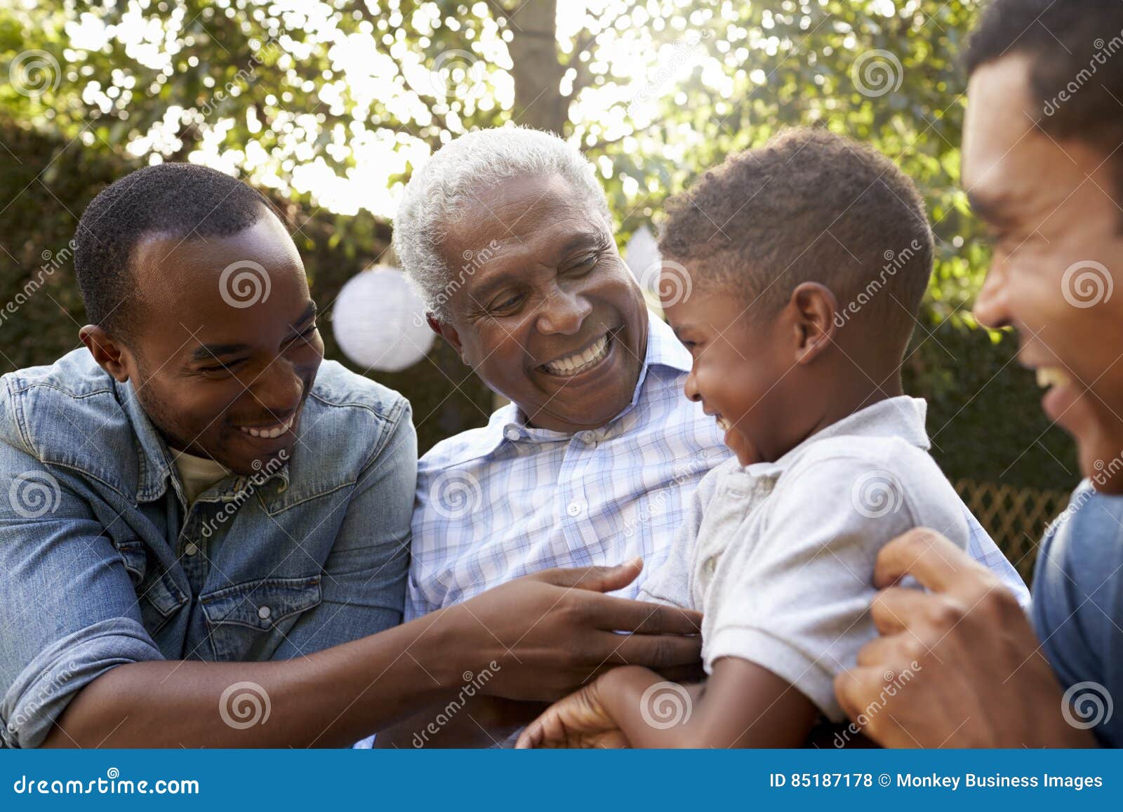 black grandfather, sons and grandson talking in a garden