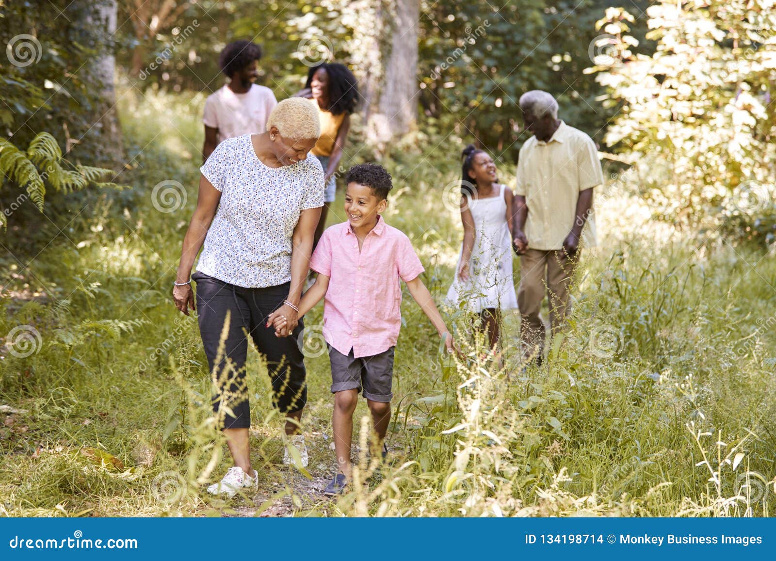black grandma walking with grandson and family, full length