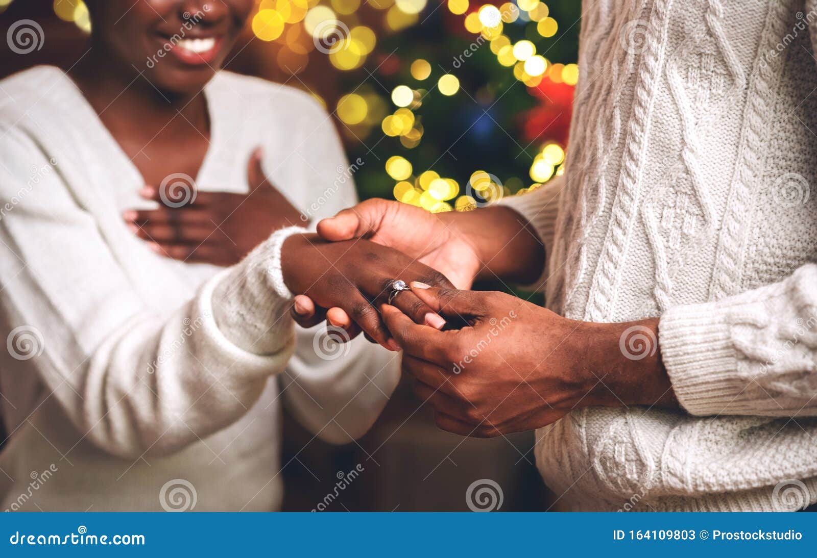 African man giving girlfriend engagement ring in Christmas tree lot - Stock  Photo - Dissolve