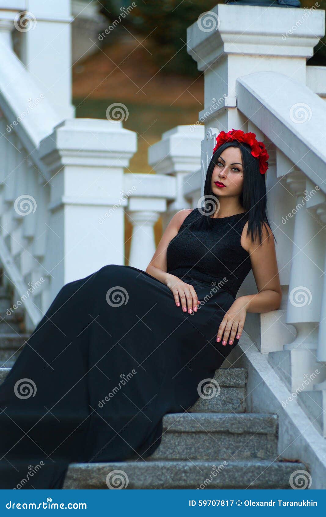 Black haired woman in the dark dress are waiting. Beautiful black haired woman with red flower chaplet are waiting at the stairs