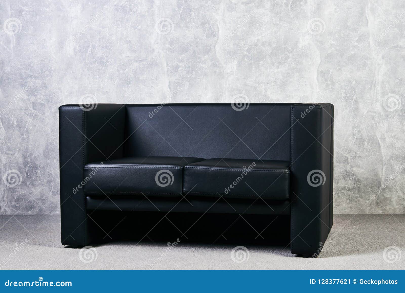 Black Leather Sofa Against Gray Textured Wall Background. Stock Image
