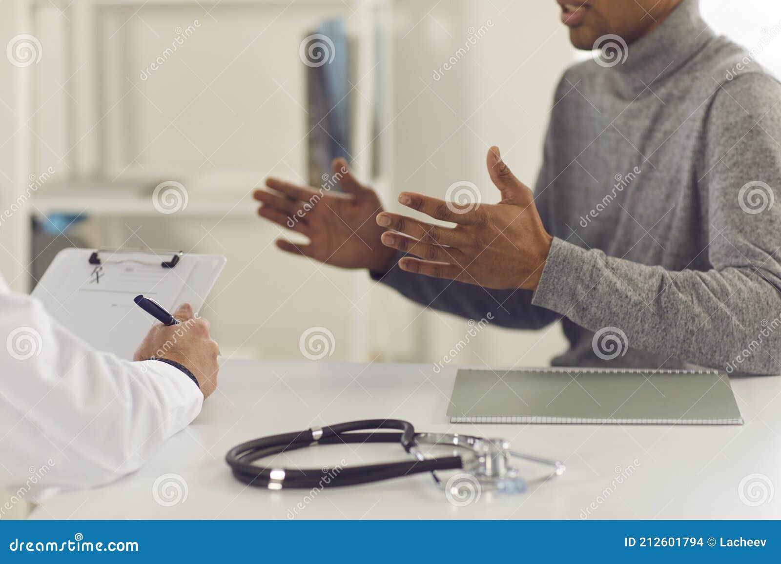 black man patient sitting and explaining health complaints to man doctor