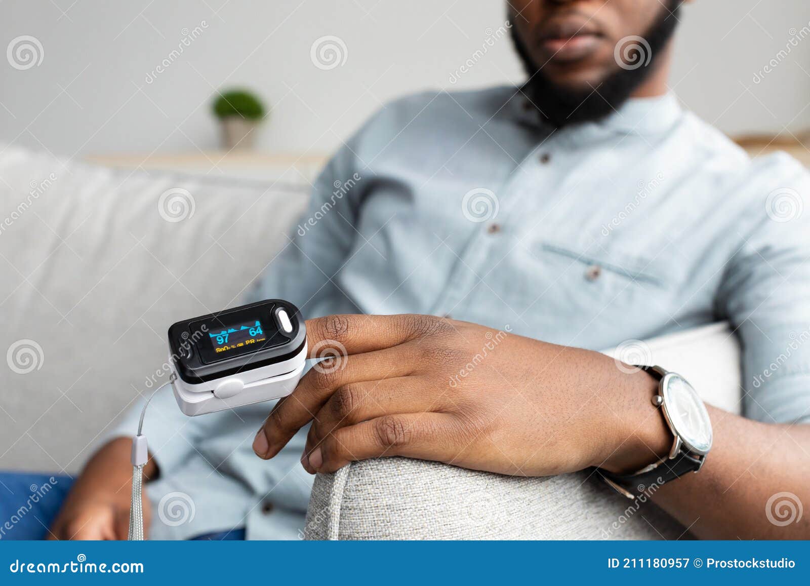 black man with pulse oximeter measuring oxygen saturation at home