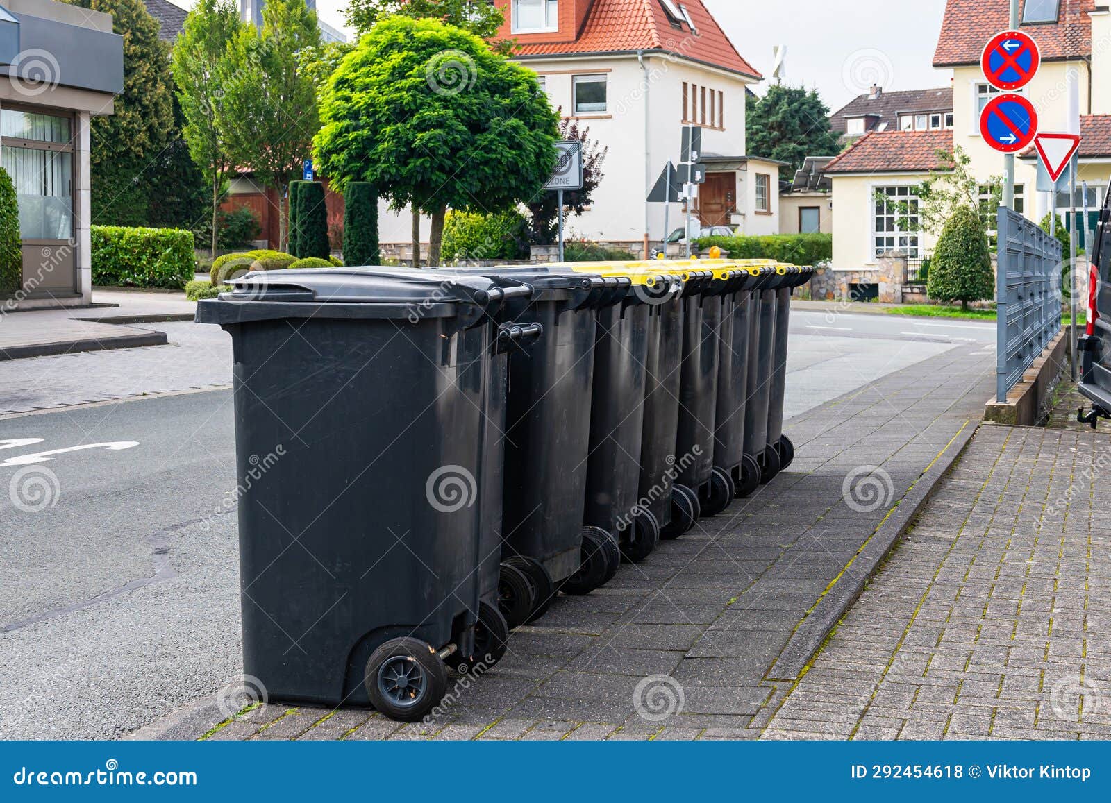 Black Plastic Trash Cans Lined Up on the Sidewalk. Stock Photo Image