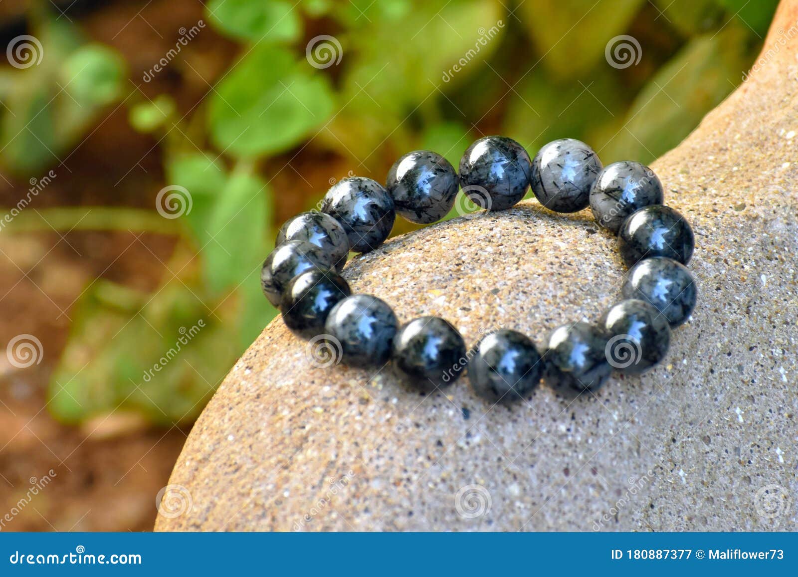 black rutilated quartz bracelet on the statue in the garden with copy space on the left side.